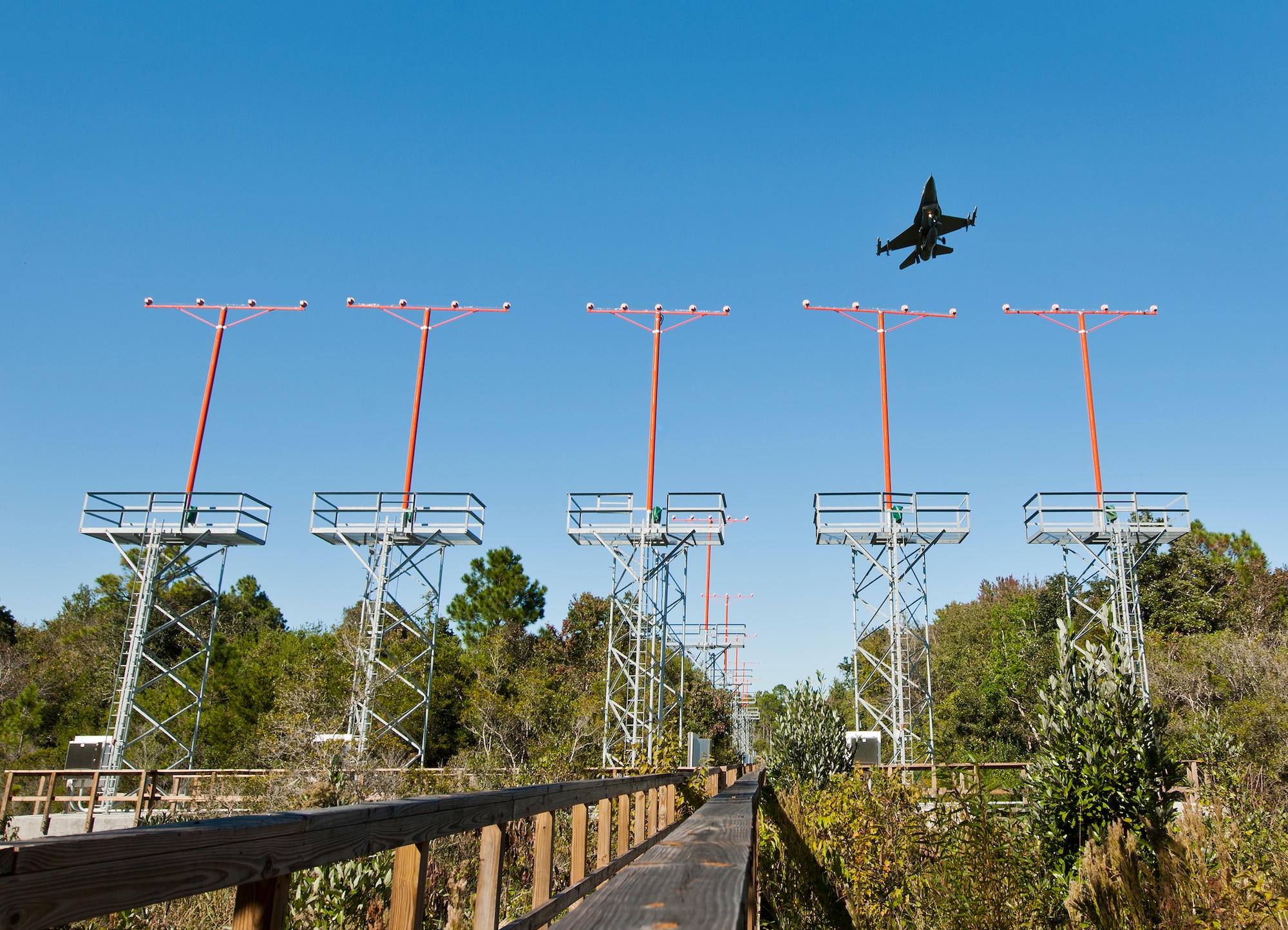 An F-16 Fighting Falcon soars over the airfield approach lighting system at the end of Runway 19 at Eglin Air Force Base, Fla.  These elevated systems at Eglin and Duke Field are maintained by the 796th Civil Engineer Squadron.  Eglin and Duke’s systems contain 60 elevated towers.   Each contains four 200-watt lamps.  Civil Engineer personnel change out approximately 60 of the 240 lamps used at the top of the spires every year.  (U.S. Air Force photo/Samuel King Jr.)