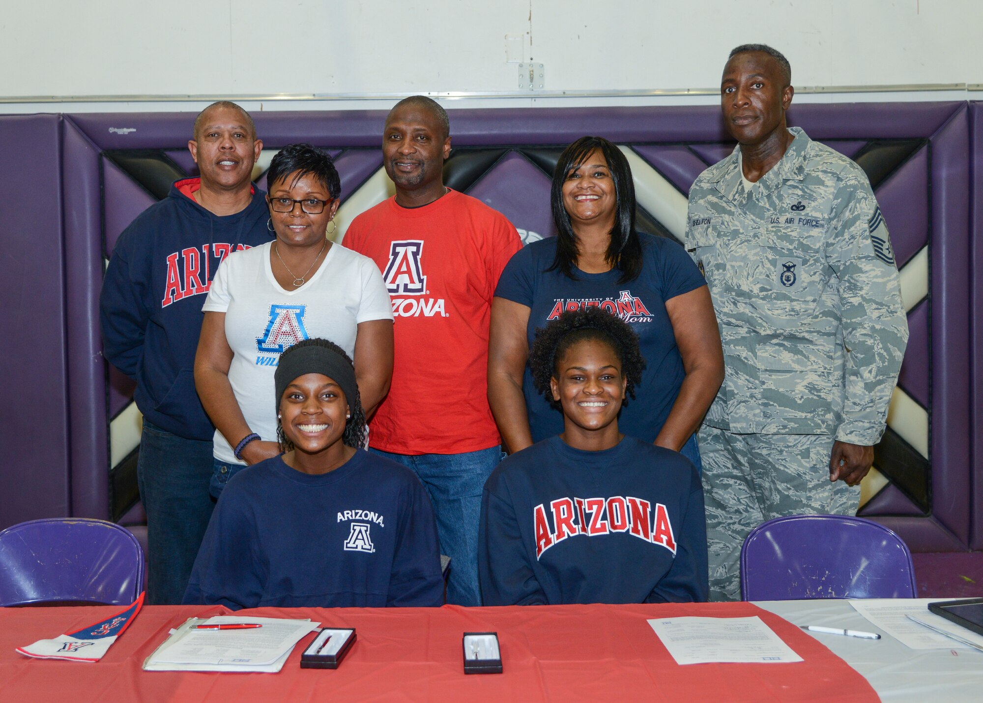 Devyn Cross (seated left) and Elizabeth Shelton signed National Letters of Intent to attend the University of Arizona next fall on volleyball scholarships Nov. 13. The students were joined by their parents (left to right) James Culver, Lisa Cross-Culver, James Culver, LaConger Shelton and Chief Master Sgt. Darrell Shelton. (U.S. Air Force photo by Rebecca Amber)