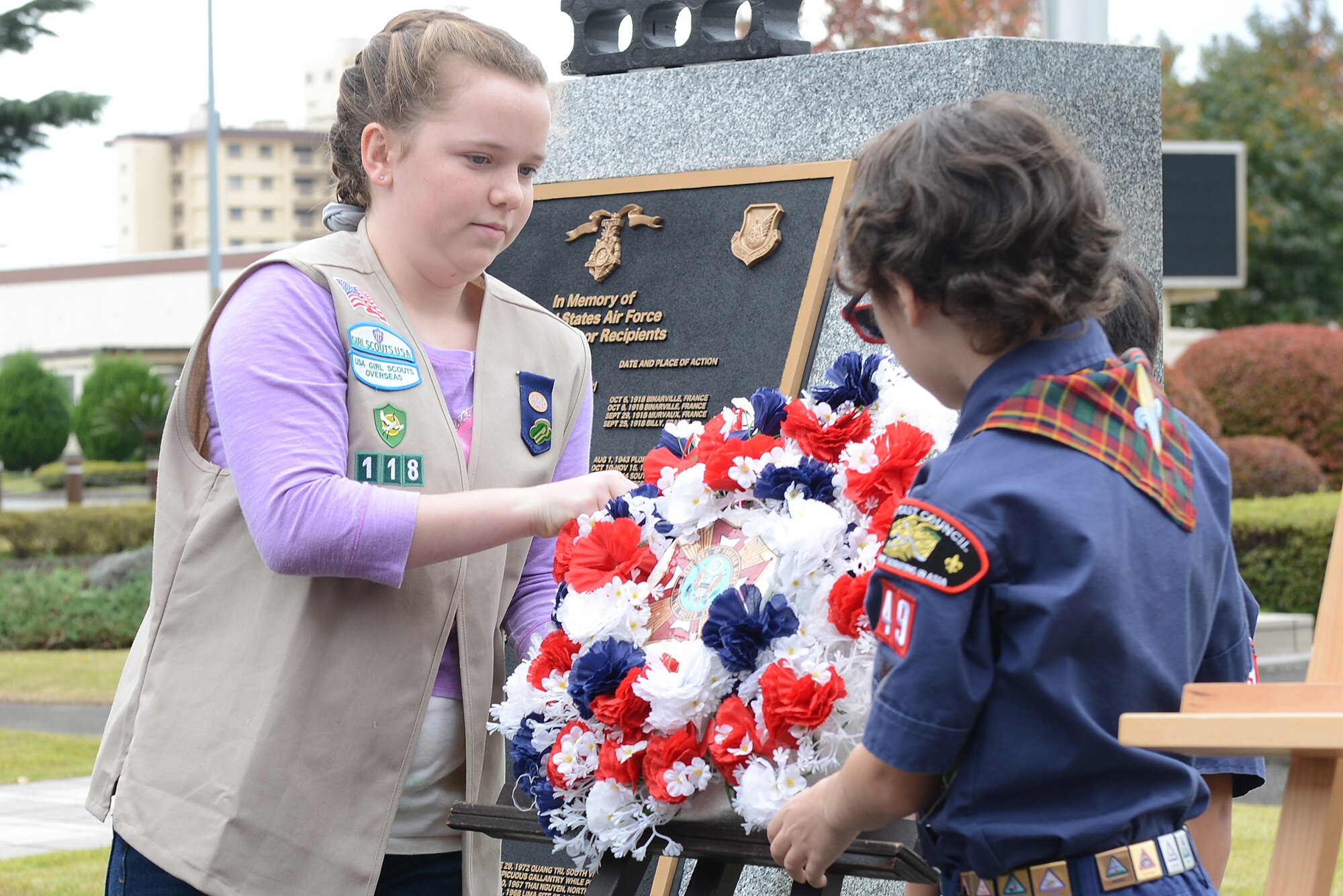 A wreath is placed on an easel by a Boy Scout and Girl Scout at Yokota Air Base, Japan, Nov. 11, 2015. The Boy Scouts of America and Girl Scouts of America took part in the Veterans Day ceremony celebrating the service of all U.S. military veterans. (U.S. Air Force photo by Senior Airman David C. Danford/Released)