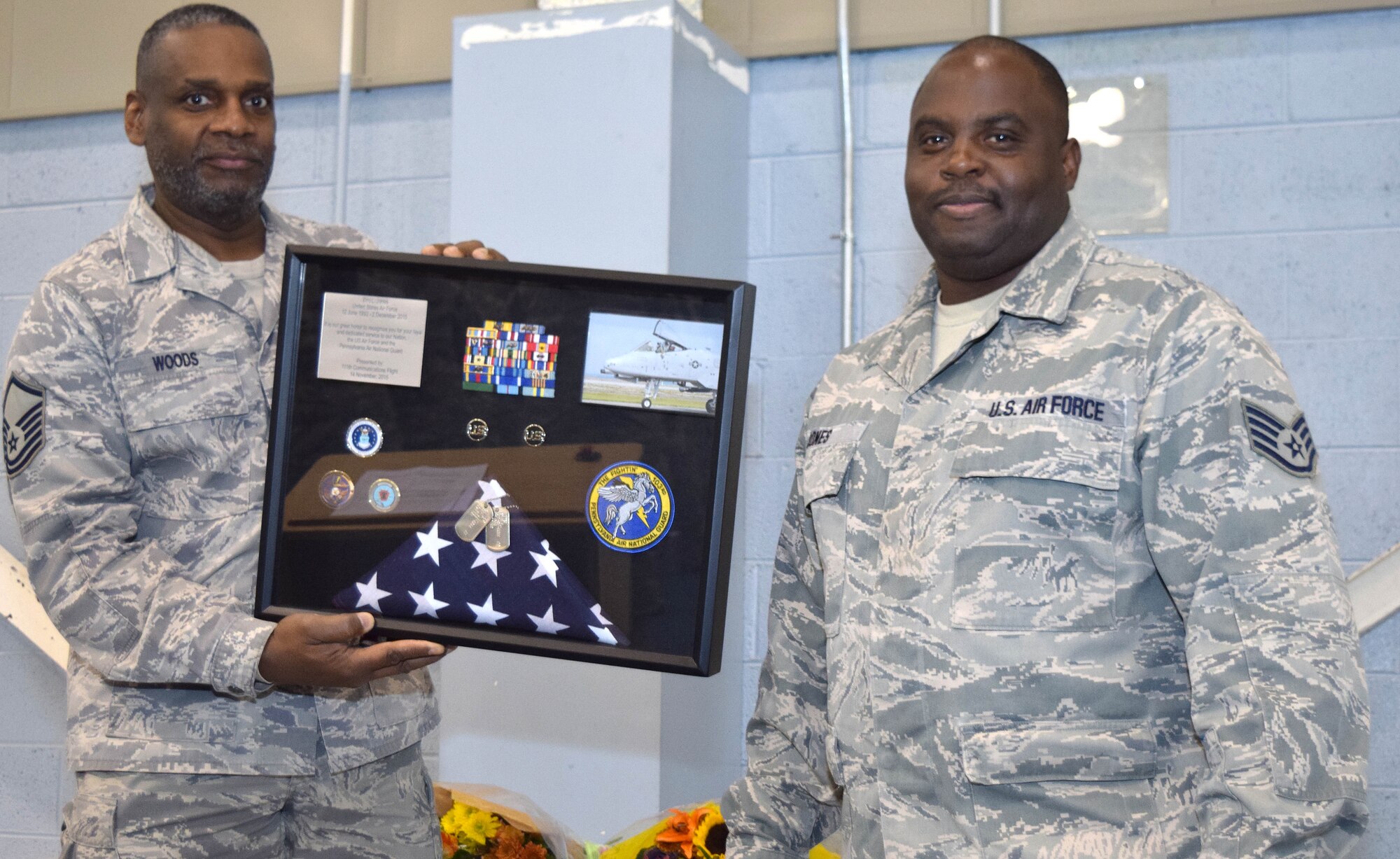 Staff Sgt. Eric Jones, information assurance noncommissioned officer of the 111th Communications Flight, stands with his shadowbox given to him by Master Sgt. Stanley Woods, a cyber surety systems specialist of the111th Attack Wing, during Jone's retirement ceremony at Horsham Air Guard Station, Nov. 14, 2015. Before transitioning into the communications career field, Jones was a crew chief on the A-10 Thunderbolt II. (U.S Air National Guard photo by Master Sgt. Chris Botzum/Released)