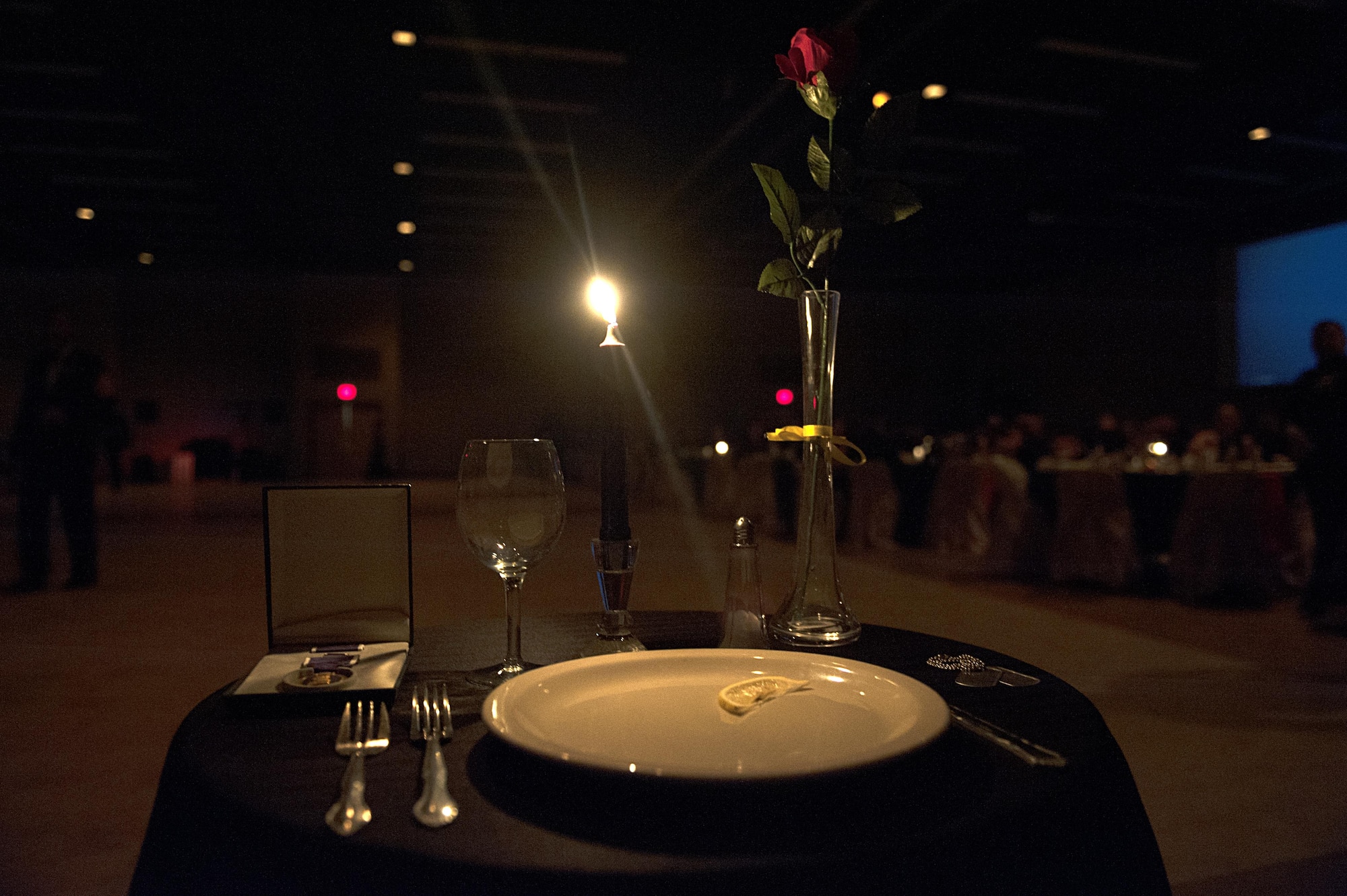 Candlelight glows from the Prisoners of War and Missing in Action table during the Unites States Marine Corps Ball at the McNease Convention Center, San Angelo, Texas, Nov. 14, 2015. The master of ceremonies lit the candle before the ceremonies started and it remained lit until the end of the event. (U.S. Air Force photo by Airman 1st Class Caelynn Ferguson/Released)