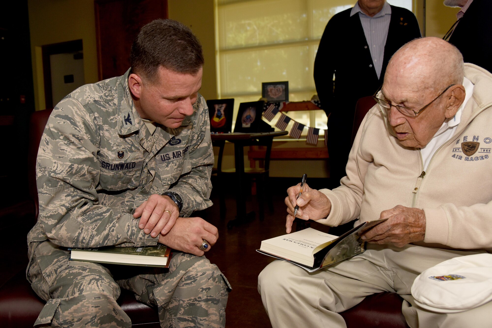 Retired U.S. Army Air Corps Lt. Col. Richard E. Cole, Doolittle Raider, signs a book for U.S. Air Force Col. Michael Grunwald Jr., 17th Training Group Commander, at the Event Center on Goodfellow Air Force Base, Texas, Nov. 12, 2015. During Cole’s visit, he provided a 30 minute Q-and-A session to Goodfellow service members and civilians. (U.S. Air Force photo by Senior Airman Joshua Edwards/Released)
