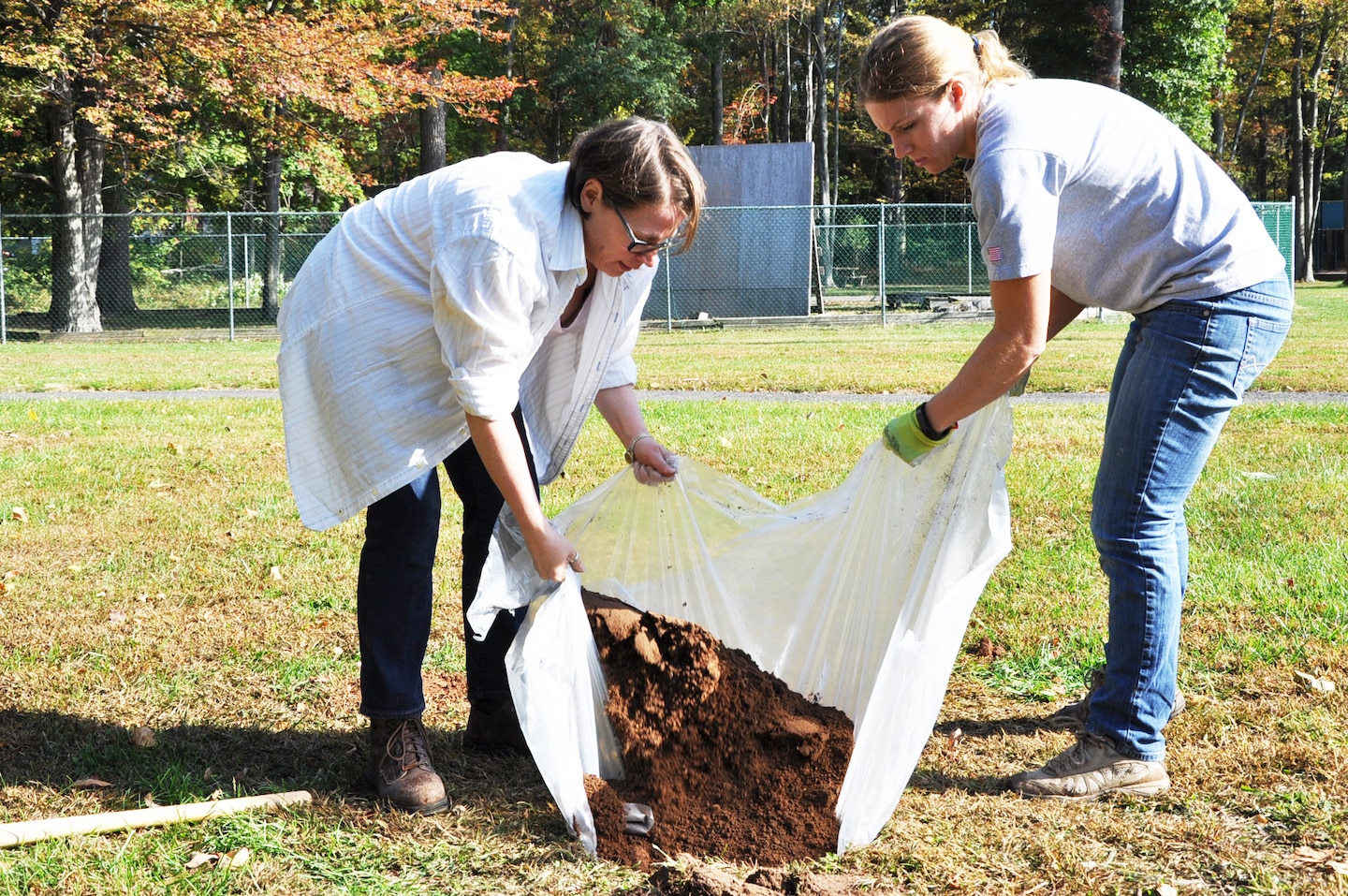 New York District archaeologists Lynn Rakos (left) and Marissa Scarpa (right) refill a hole searching for artifacts on the grounds of Green Brook Middle School in Green Brook, New Jersey, October 21. The plastic ground cover catches dirt from a sifter, limits impact on the excavated area, and makes it easier to refill test holes.  