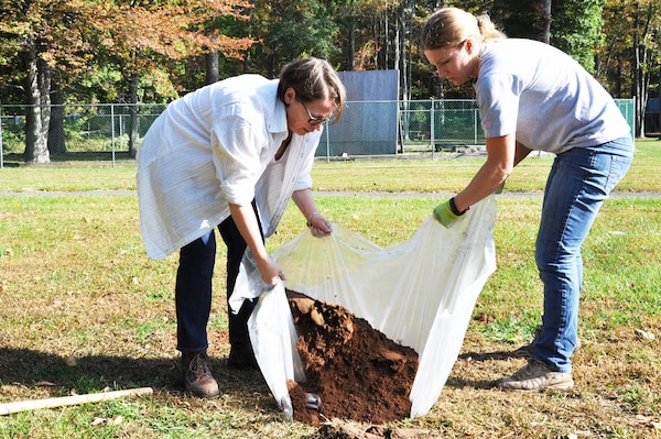 New York District archaeologists Lynn Rakos (left) and Marissa Scarpa (right) refill a hole searching for artifacts on the grounds of Green Brook Middle School in Green Brook, New Jersey, October 21. The plastic ground cover catches dirt from a sifter, limits impact on the excavated area, and makes it easier to refill test holes.  