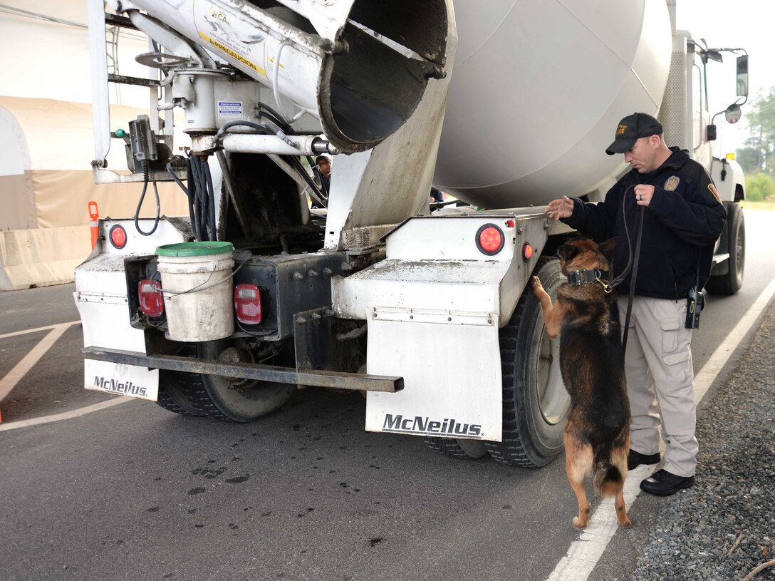Cpl. Erin Zupko, police officer/K-9 handler, Marine Corps Police Department, Marine Corps Logistics Base Albany, and his military working dog, Meta, walk the perimeter of a commercial vehicle during a checkpoint inspection at the new Mock Road Gate, recently. All commercial vehicles entering the installation are required to go through security protocols before access is granted. Opening of the new entrance, Nov. 16, officially closes the Fleming Road Gate 5 to commercial vehicles and alleviates congestion for early morning commuters to the installation.