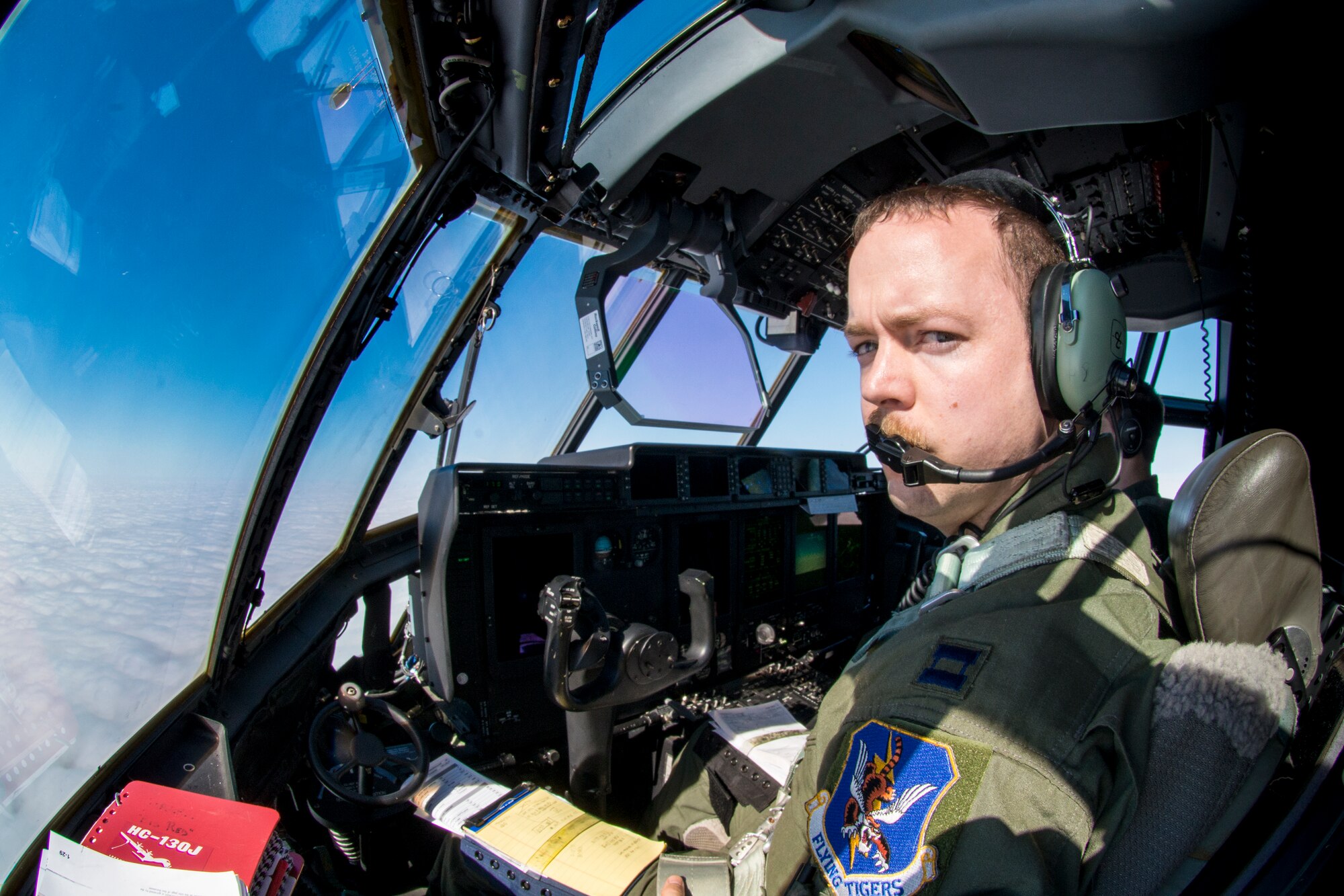 U.S. Air Force Capt. James Corless, 71st Rescue Squadron HC-130J Combat King II pilot, reaches for a visor to block the sun, Nov. 10, 2015, in the skies over Moody Air Force Base, Ga. HC-130J pilots are tasked with airdrop, helicopter air-to-air refueling, humanitarian assistance and aeromedical evacuation missions. (U.S. Air Force photo by Senior Airman Ryan Callaghan/Released)


