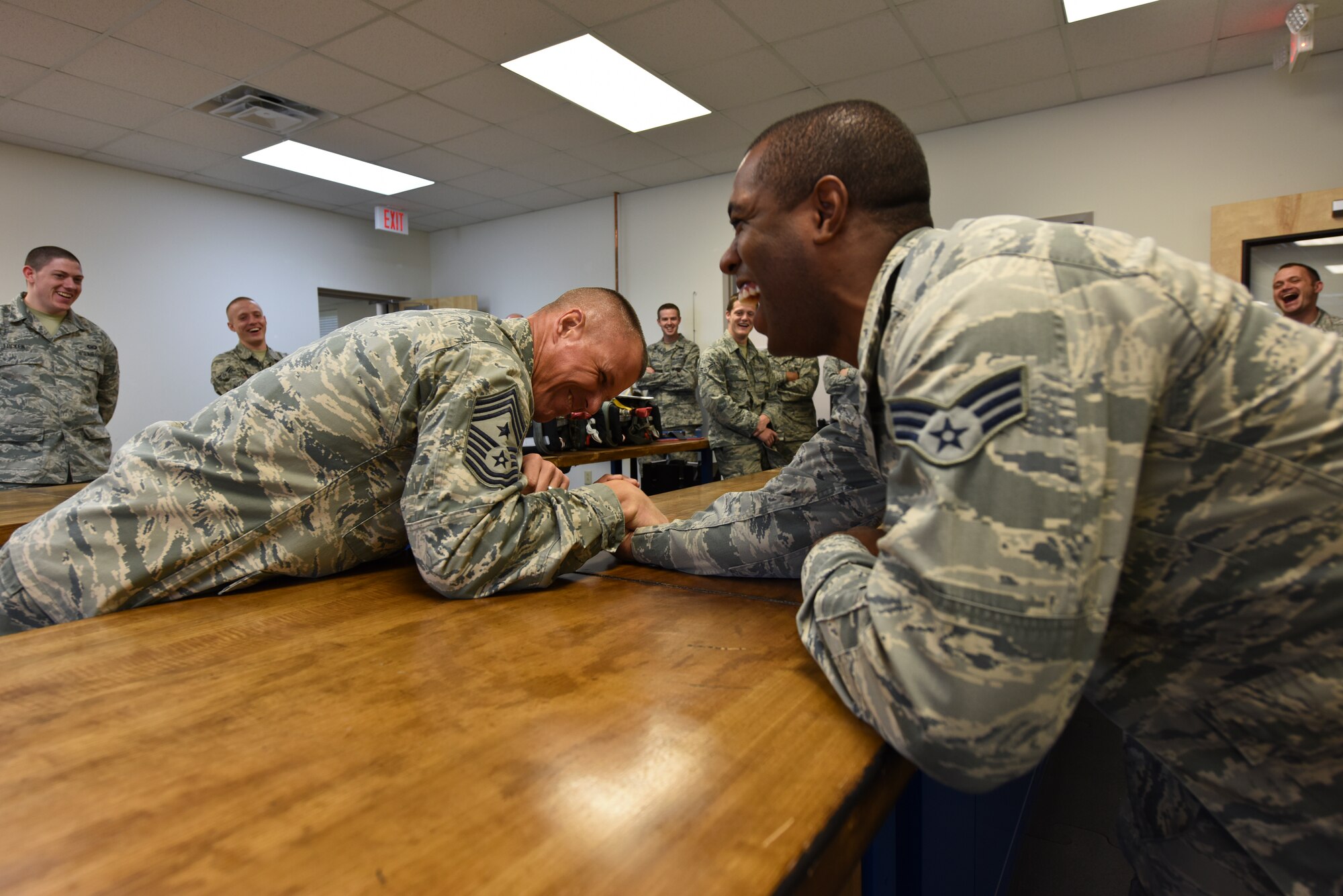 Chief Master Sgt. Steve McDonald (left), Air Combat Command command chief, arm wrestles with Senior Airman Kailyn Moore, 4th Operations Support Squadron aircrew flight equipment technician, during an installation visit, Nov. 12, 2015, at Seymour Johnson Air Force Base, North Carolina. McDonald interacted with Airmen at each office he visited during his 3-day stay to discuss current issues and Airman resilience. (U.S. Air Force photo/Senior Airman Aaron J. Jenne)