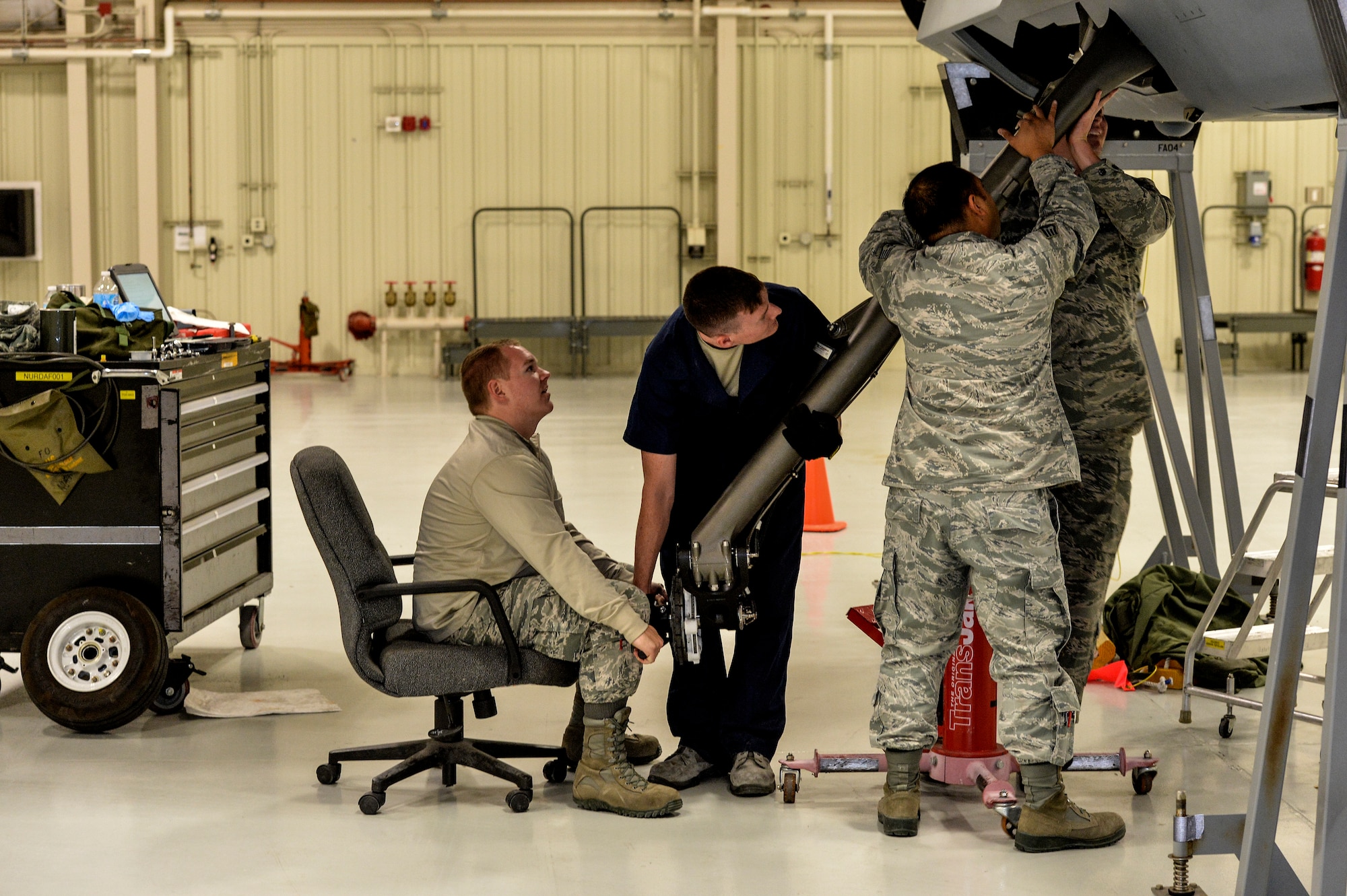 Instructors and Students place landing gear into an aircraft at Creech Air Force Base, Nevada. Nov. 6, 2015. Det 13 OL-A provides maintenance training to the MQ-1/9 enterprise. Crew Chiefs, Avionics, Weapons and Communications courses are offered from our staff of 6 AETC instructors