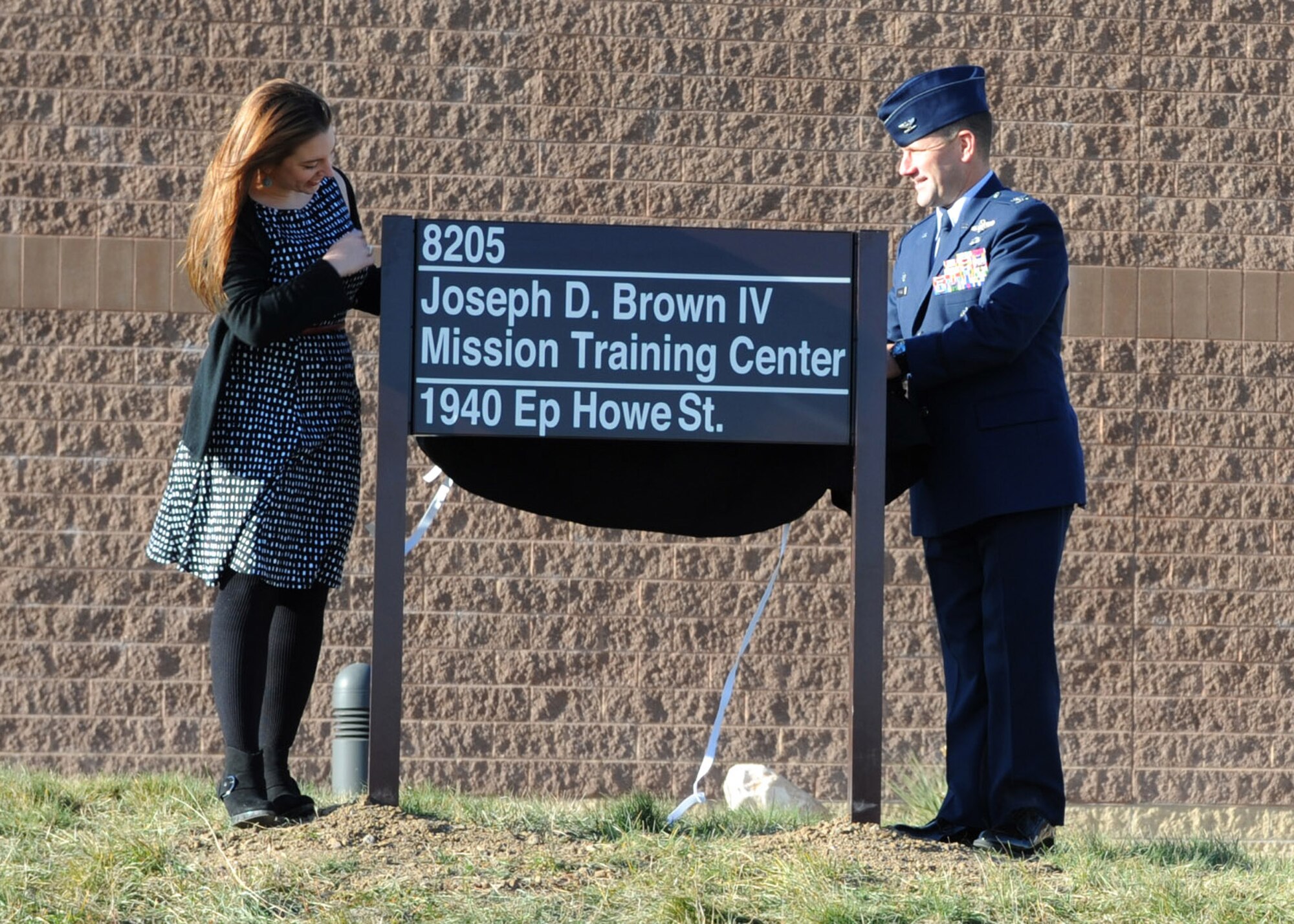 Col. Gentry Boswell, right, 28th Bomb Wing commander, and Emily Brown, left, daughter of late Maj. Gen. Joseph D. Brown IV, unveil the new name of the Mission Employment Center during a building dedication ceremony at Ellsworth Air Force Base, S.D., Nov. 10, 2015. The building was dedicated to Brown for his service and passion for the Air Force, its mission and team Ellsworth. (U.S. Air Force photo by Airman 1st Class Denise M. Nevins/Released)