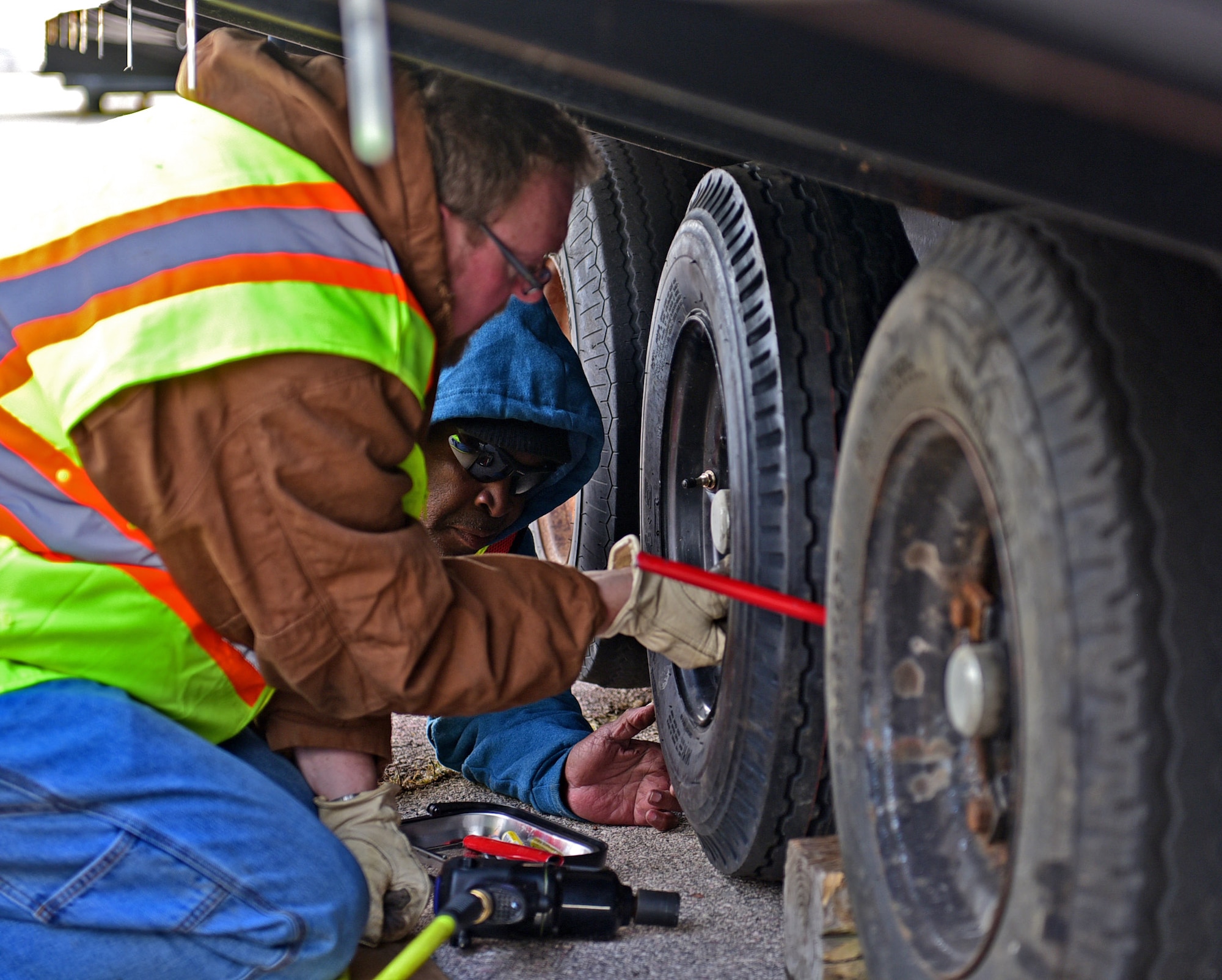 Sam Weldon, Federal Emergency Management Agency logistics management specialist, tightens a tire bolt with the assistance of Calvin Rock, FEMA logistics management specialist, at the alert pad at Ellsworth Air Force Base, S.D., Nov. 5, 2015. Weldon and Rock are part of a nine-person team responsible for the upkeep and repair of manufactured homes temporarily stored on base before they are sent to Pine Ridge Indian Reservation. (U.S. Air Force photo by Airman 1st Class James L. Miller/Released)