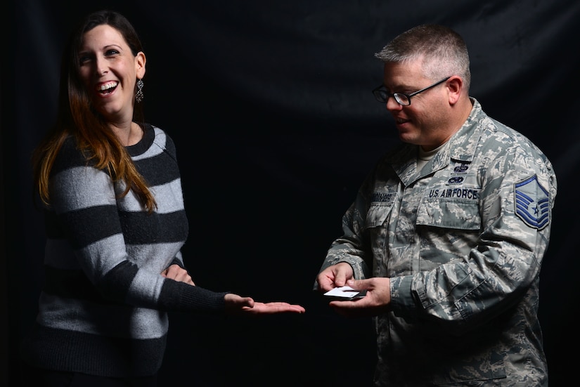 Alisa Deuermeyer, volunteer at Joint Base Langley-Eustis, Va., laughs as U.S. Air Force Master Sgt. Scott Fridinger, additional duty first sergeant assigned to the Air Combat Command Communications Support Squadron, performs a card trick at Langley Air Force Base, Va., Oct. 21, 2015. As the acting first sergeant, Fridinger said he finds his magic beneficial to build rapport with the Airmen he oversees, while enhancing their morale. (U.S. Air Force photo by Senior Airman Aubrey White)