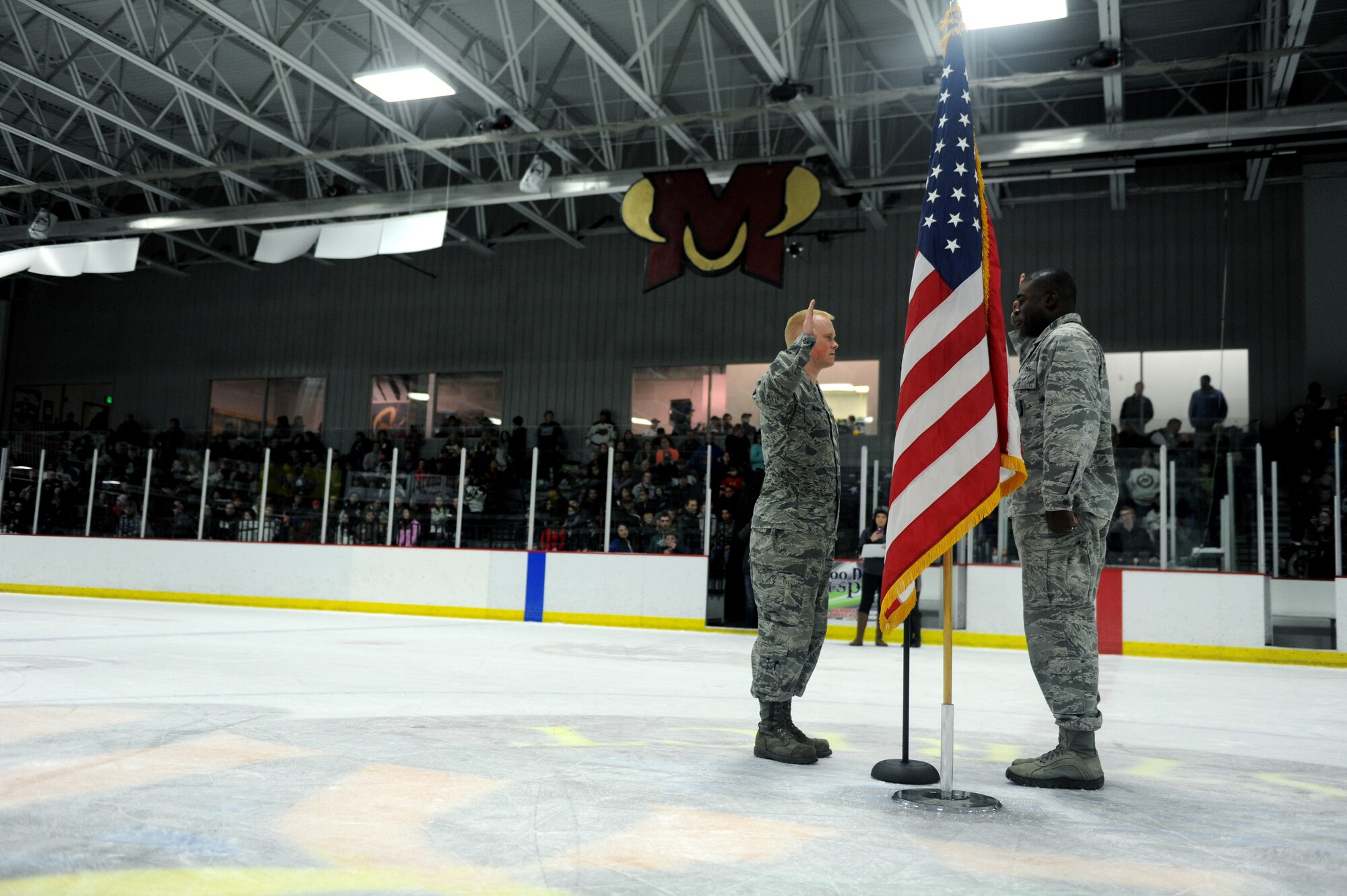 Capt. Lamin Jackson reenlists Senior Airman Brandon Gilmore, both 91st Maintenance Sq. at the Minot Minotaurous game in Minot, N.D. Nov. 10, 2015. Gilmore reenlisted during the game where veterans were honored for Veteran’s Day. (U.S. Air Force photo by Staff Sgt. Chad Trujillo)