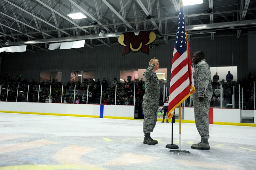 Capt. Lamin Jackson reenlists Senior Airman Brandon Gilmore, both 91st Maintenance Sq. at the Minot Minotaurous game in Minot, N.D. Nov. 10, 2015. Gilmore reenlisted during the game where veterans were honored for Veteran’s Day. (U.S. Air Force photo by Staff Sgt. Chad Trujillo)