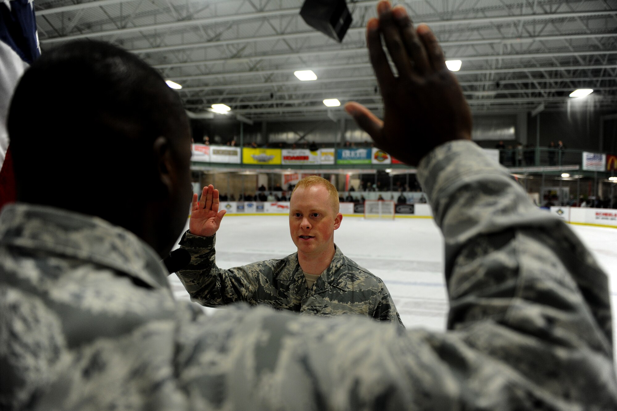 Capt. Lamin Jackson reenlists Senior Airman Brandon Gilmore, both 91st Maintenance Squadron at the Minot Minotaurous game in Minot, N.D. Nov. 10, 2015. Gilmore reenlisted during the game where veterans were honored for Veteran’s Day. (U.S. Air Force photo by Staff Sgt. Chad Trujillo)