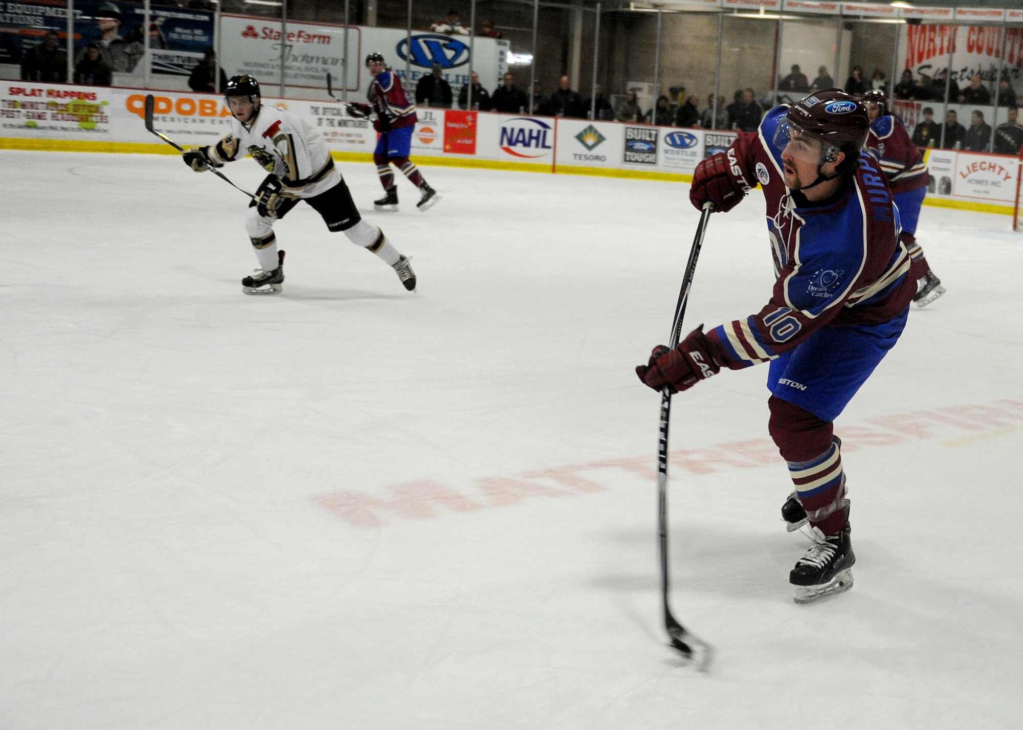 A member from the Minot Minotauros team hits a puck during a game against the Bismarck Bobcats in Minot, N.D. Nov. 10, 2015. The game was honored military veterans for Veteran’s Day. (U.S. Air Force photo by Staff Sgt. Chad Trujillo)