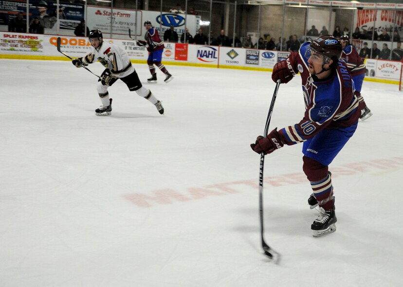 A member from the Minot Minotauros team hits a puck during a game against the Bismarck Bobcats in Minot, N.D. Nov. 10, 2015. The game was honored military veterans for Veteran’s Day. (U.S. Air Force photo by Staff Sgt. Chad Trujillo)