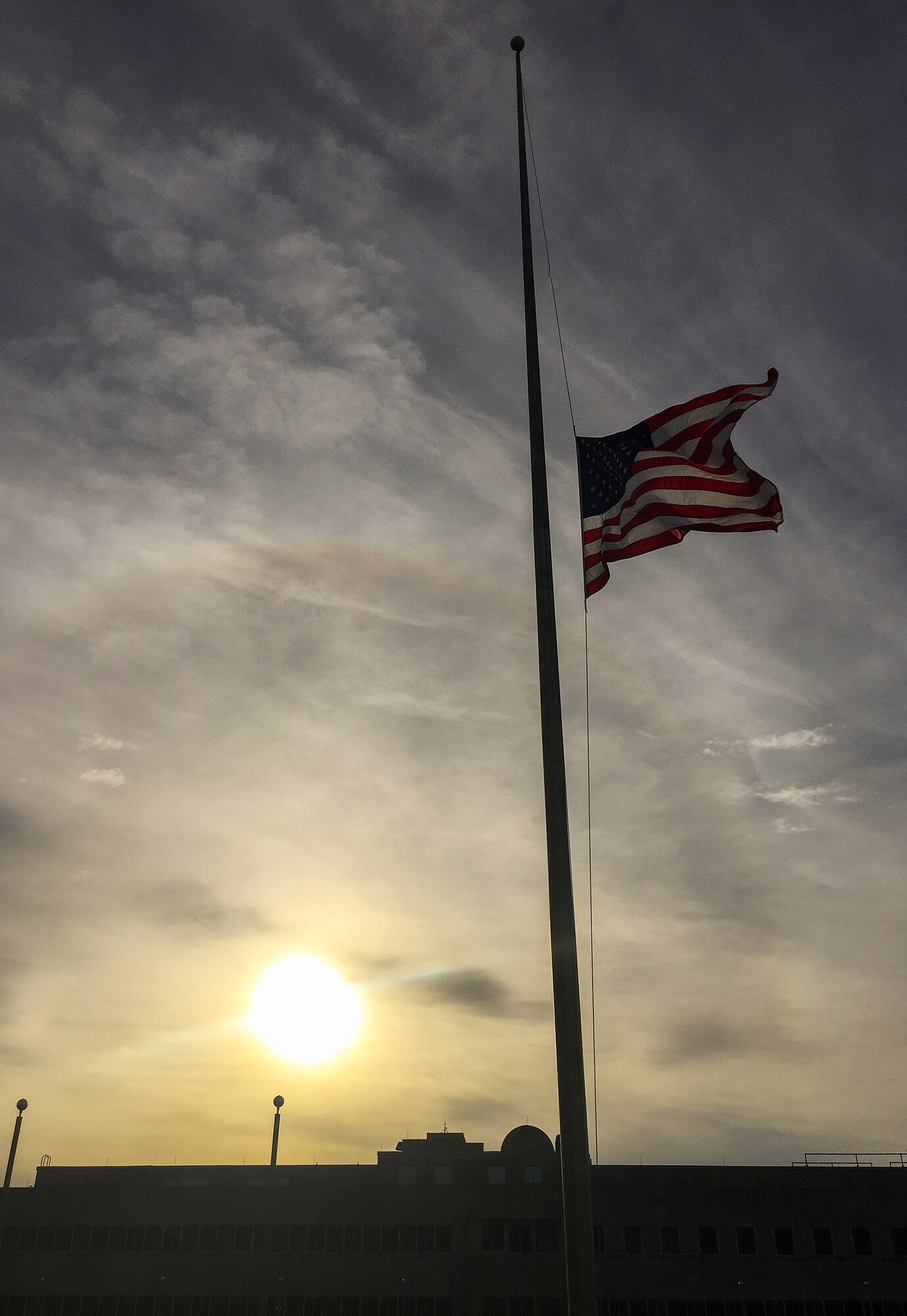 The sun rises over the lowered base headquarters American flag Nov. 17 at Eglin Air Force Base, Fla.  All government agency American flags were lowered to half-staff through Nov. 19 in solidarity to France after the recent terrorist attacks.  (U.S. Air Force photo/Samuel King Jr.)