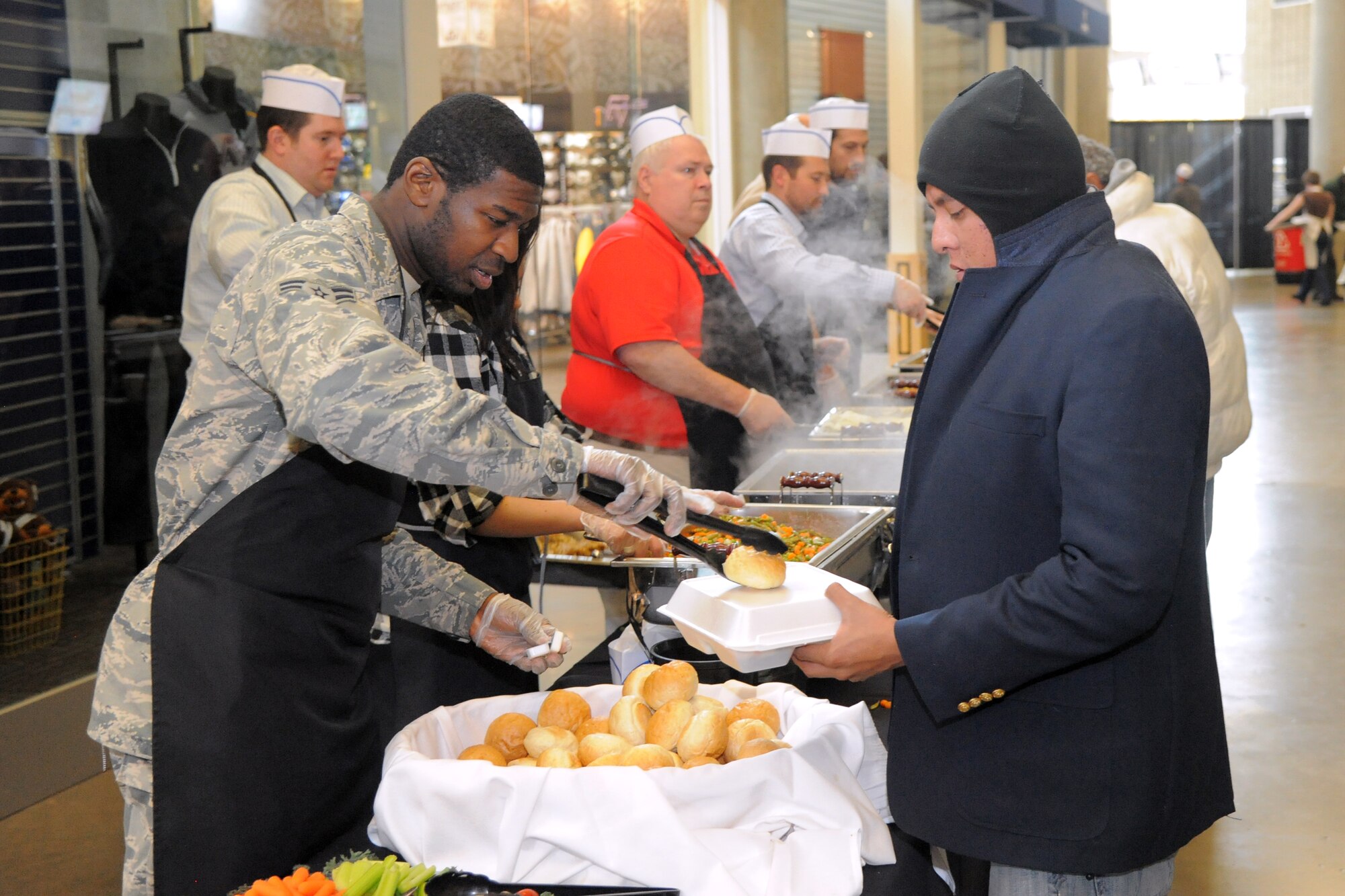 Airman 1st Class McKethan Campbell, 75th Medical Group, serves a hot Thanksgiving meal to a local resident Nov. 16 at Vivant Smart Home Arena in downtown Salt Lake City. Campbell and other volunteers from Hill Air Force Base participated in the 17th annual “We Care-We Share event, which benefited thousands of homeless and low-income Utah residents. (U.S. Air Force photo by Todd Cromar)