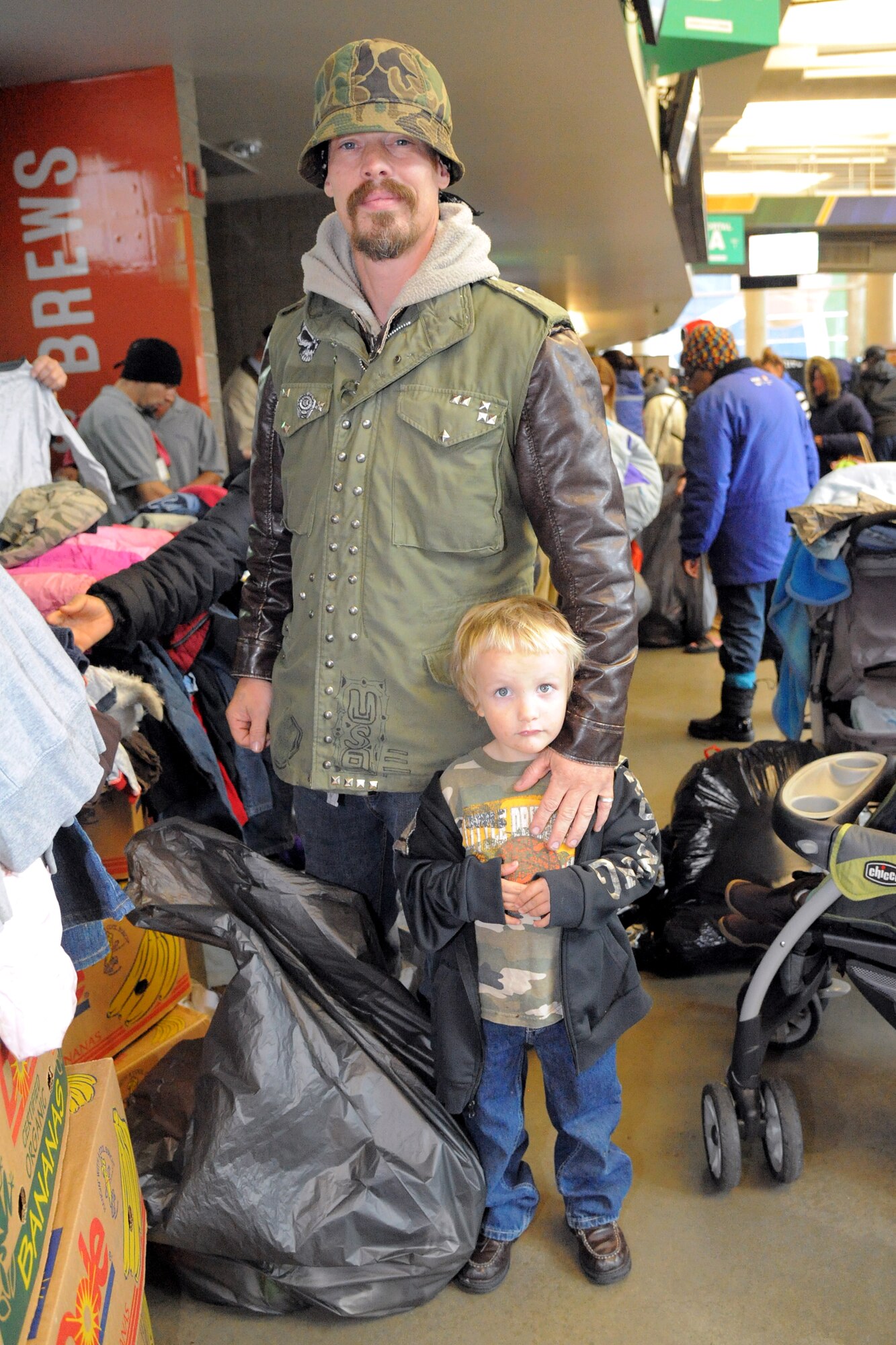 Gary Frank and his son Liam pose for a photo while receiving winter clothing items during the 17th annual community outreach event called We Care-We Share Nov. 16 at Vivint Smart Home Arena, Salt Lake City, Utah. The event, hosted by Larry H. Miller Sports and Entertainment, helped thousands of homeless and low-income Utah residents. (U.S. Air Force photo by Todd Cromar)