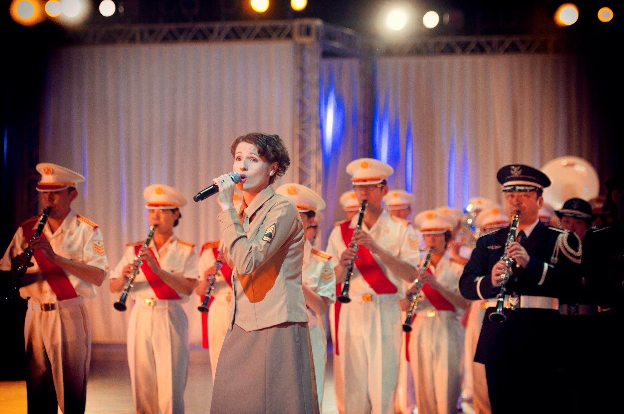 Senior Airman Joanne Griffin, U.S. Air Force Band of the Pacific vocalist, performs alongside Japan Air and Ground Self-Defense Force members during the Japan Self-Defense Force Marching Festival at the Nippon Budokan Arena in Tokyo, Japan, Nov. 13, 2015. The show featured performances by more than one thousand musicians from various marching bands and drill teams throughout each branch of the JSDF as well as U.S. Army, Navy, and Marine Corps bands. (U.S. Air Force photo by Airman 1st Class Delano Scott/Released)     