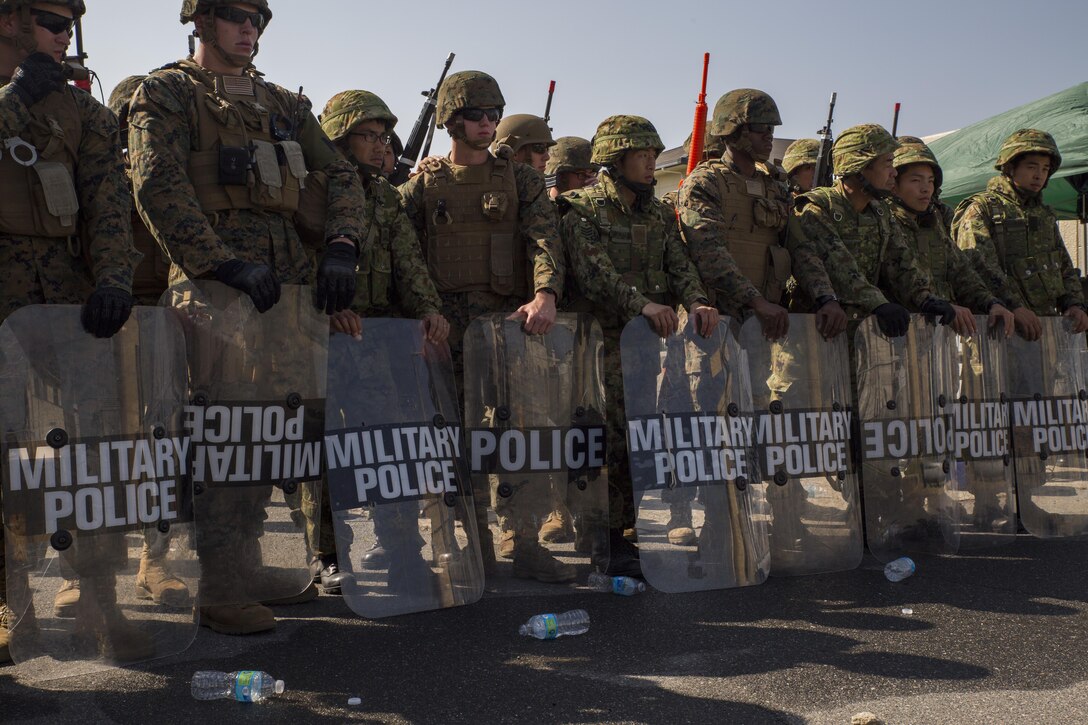 Marines and Japan Ground Self-Defense Force soldiers take a stance after a simulated riot control situation during Exercise Guard and Protect at Marine Corps Air Station Iwakuni, Japan, Oct. 20-23, 2015. Marines and JGSDF soldiers were challenged with real world situations such as riot control, armed intruder response and vehicle searches to prepare in case the air station has to take a defense posture.
