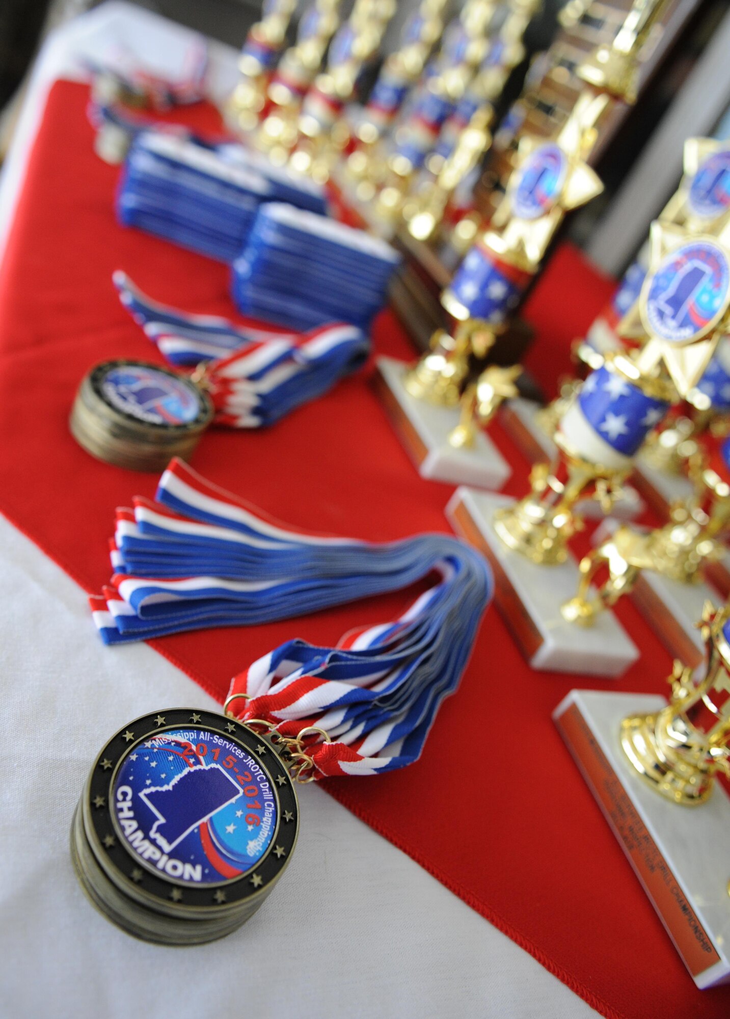 Medals and trophies sit on display during the second annual Mississippi All-Services Junior ROTC Drill Competition Nov. 14, 2015, at Keesler Air Force Base, Miss. Seventeen Junior ROTC teams from all military branches were represented at the event. Approximately 800 Junior ROTC cadets and spectators were in attendance where cadets battled for the best all-services Junior ROTC team for Mississippi. Recruiting booths and static displays, including military vehicles, equipment and an aircraft were available to the cadets throughout the competition. (U.S. Air Force photo by Kemberly Groue)