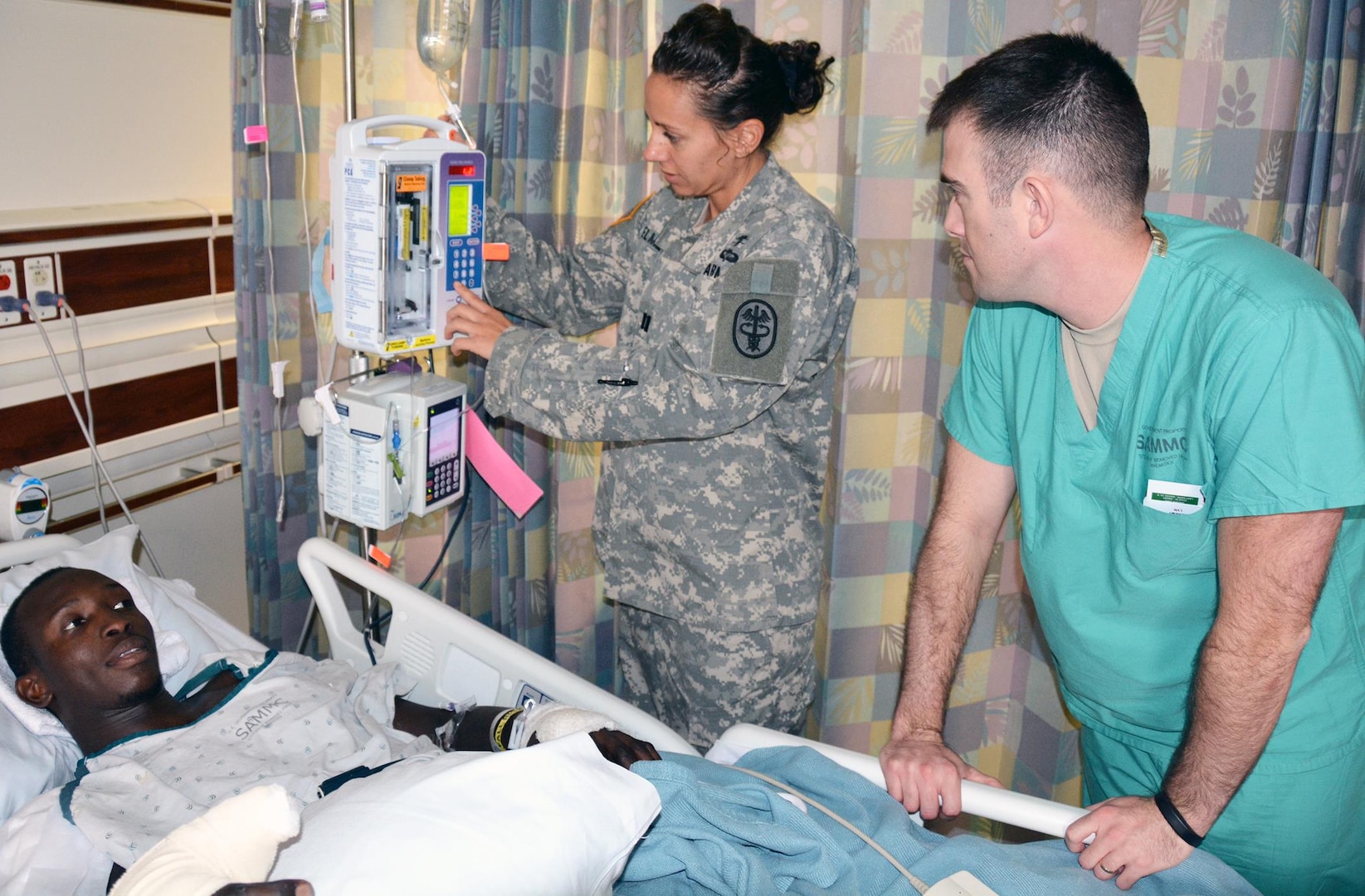 Capt. Kelly Elmlinger (center), an Army nurse, checks on patient Papa Ndiaye while Army Spc. Jeremy Allred looks on in the 4 West inpatient ward at the San Antonio Military Medical Center on Joint Base San Antonio-Fort Sam Houston Oct. 23.