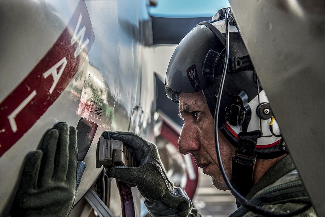 U.S. Navy Cmdr. David B. Waidelich checks a fire extinguisher pressure gauge of an E-2C Hawkeye on the flight deck of the aircraft carrier USS Ronald Reagan during a change of command ceremony in the Philippine Sea, Nov. 14, 2015. The carrier and its embarked air wing, Carrier Air Wing 5, provide a combat-ready force that protects and defends the collective maritime interests of the United States and its allies and partners in the Indo-Asia-Pacific region. U.S. Navy photo by Petty Officer 3rd Class Nathan Burke