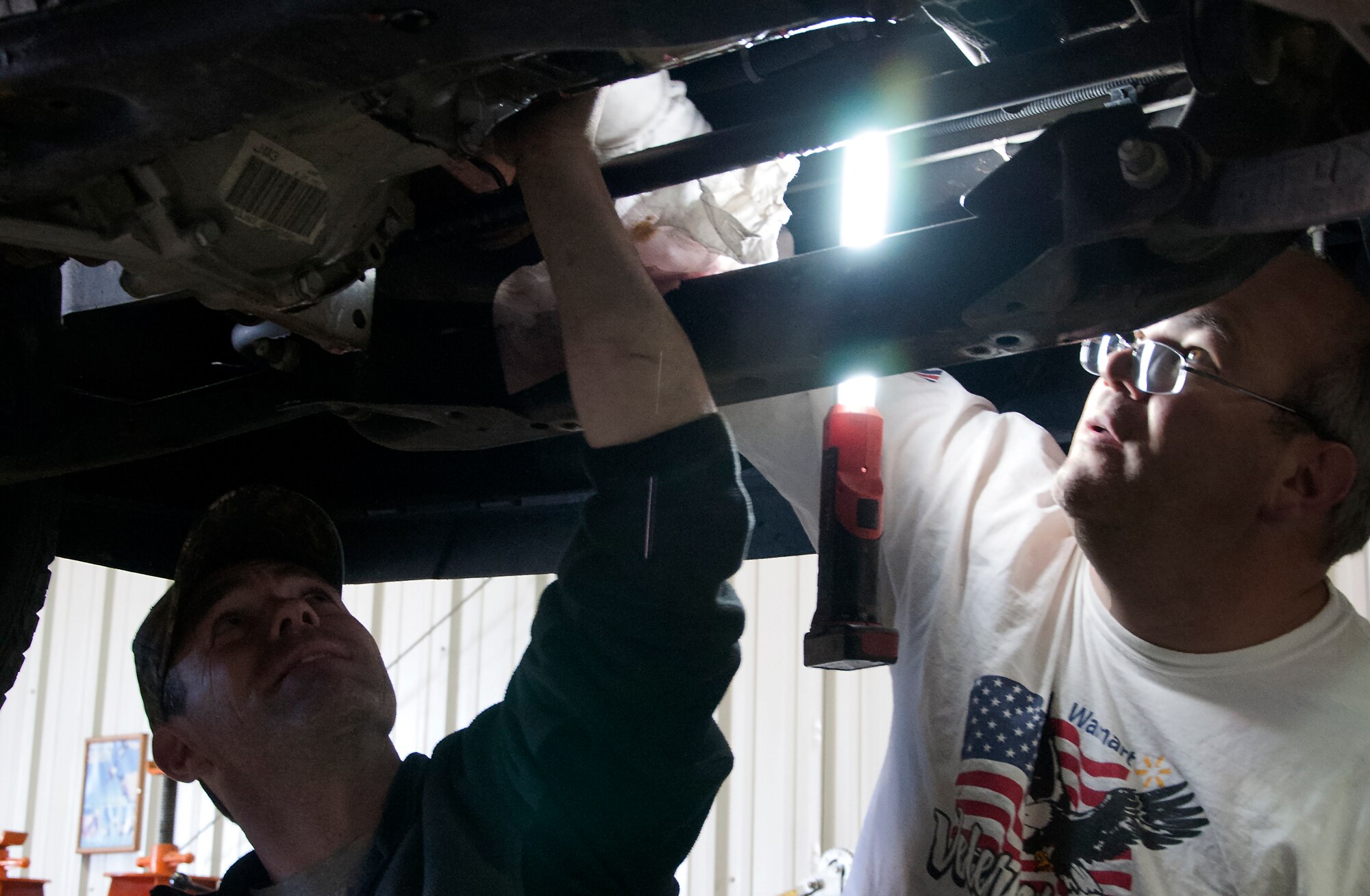 Retired Tech. Sgt. Timothy Staples and Retired Master Sgt. Chad Colgate work together to replace a fuel pump on Colgate’s truck Nov. 13, 2015, in the Auto Skills Shop on F.E. Warren Air Force Base, Wyo. The Auto Skills Shop provides access for Airmen, retirees and their families to use lifts and tools to work on vehicles. (U.S. Air Force photo by Senior Airman Brandon Valle)
