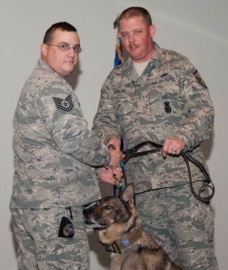 Master Sgt. Matthew Bowling (right), the 71st Security Forces Squadron operations superintendent, passes the leash of military working dog Samo to Tech. Sgt. Shawn Brunzdo, the 71st SFS kennel master, during Samo’s retirement ceremony Nov. 10 in the Base Auditorium. Brundzo, one of the dog’s prior handlers, adopted Samo. Military Working Dog handlers are afforded the opportunity to adopt their partners upon the dog’s retirement. (U.S. Air Force photo / Staff Sgt. Nancy Falcon)