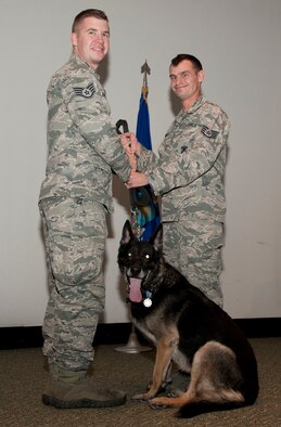 Staff Sgt. Scott Hunt (right), a 71st Security Forces Squadron military working dog handler, passes the leash of military working dog Maxik to Staff Sgt. Marshall Rains, Maxik’s previous handler, during the dog’s retirement ceremony Nov. 10 in the Base Auditorium. Rains served two years with Maxik and adopted him after the retirement. (U.S. Air Force photo / Staff Sgt. Nancy Falcon) 