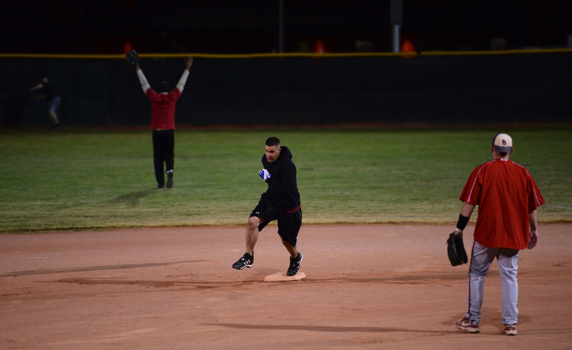 Airman 1st Class Levi Paulaydt, 61st Aircraft Maintenance Unit player, corners second base as 56th Medical Group defenders behind him scramble to get the ball back to the diamond at Luke Air Force Base, Nov. 17, 2015. The 61st AMU softball team advances in the Luke intramural tournament after defeating the 56th MDG. (U.S. Air Force photo by Airman 1st Class Ridge Shan)