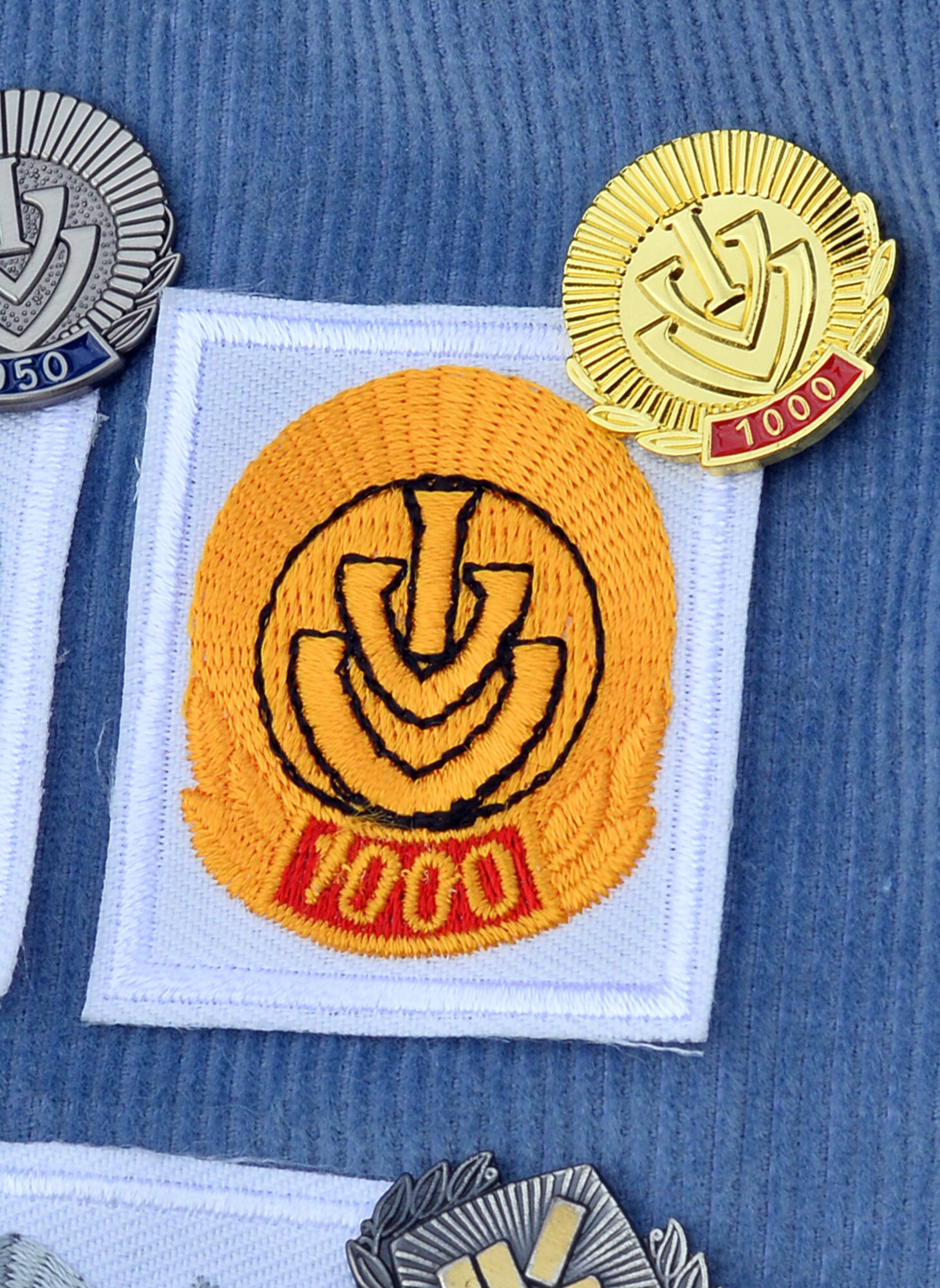 The official 1,000th event Internationaler Volkssportverband, IVV, pin and patch adorn a rectangular swatch of fabric decorated with several other milestone achievements in Volksmarching, Nov. 6, Offutt Air Force Base, Neb.  Volkmarching is a non-competitive 3.1 or 6.2 mile walk held at sanctioned IVV events around the world.  The United States volksport clubs fall under the American Volkssport Association.  (U.S. Air Force photo by Josh Plueger/Released)