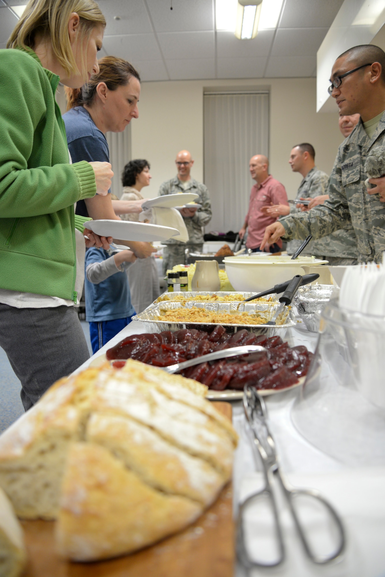 Team Mildenhall families process through a serving line during a Hearts Apart event for families of deployed Airmen Nov. 17, 2015, at the base chapel on RAF Mildenhall, England. The 100th Air Refueling Wing Staff Agencies and the 100th Comptroller Squadron provided a Thanksgiving meal, games and activities to help bring Team Mildenhall families closer together. (U.S. Air Force photo by Staff Sgt. Micaiah Anthony/Released)