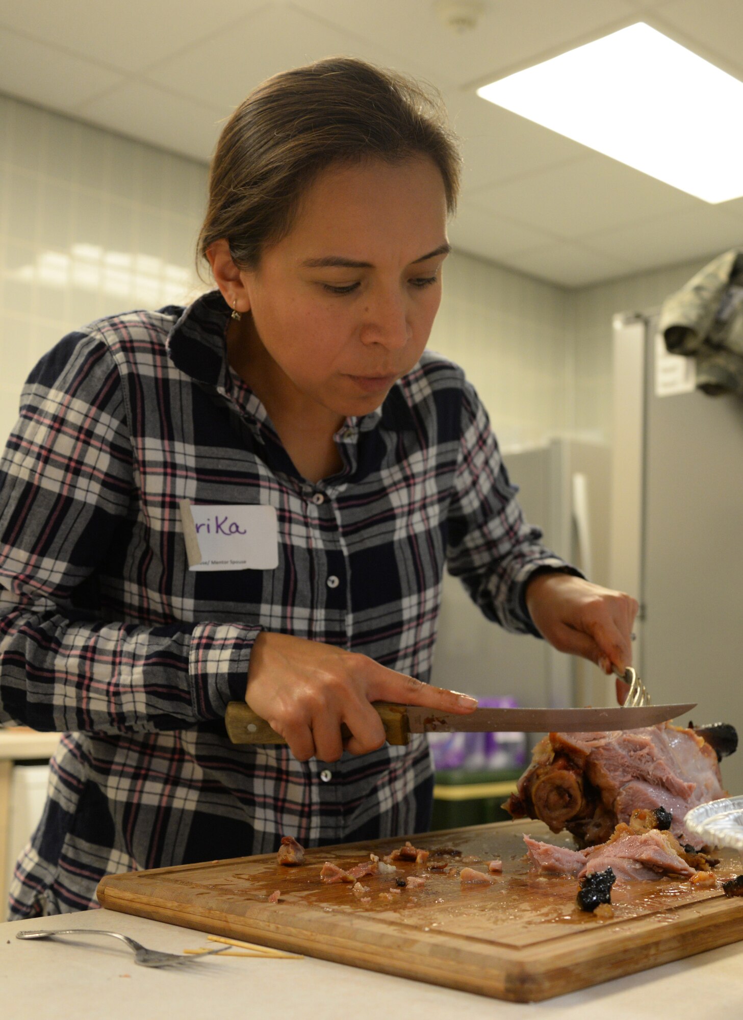 Erika Holcomb, wife of Lt. Col. Jason Holcomb, 100th Comptroller Squadron commander, cuts ham during a Hearts Apart event for families of deployed Airmen Nov. 17, 2015, at the base chapel on RAF Mildenhall, England. The 100th Air Refueling Wing Staff Agencies and the 100th CS hosted the monthly event which helps bring Team Mildenhall families closer together during times of separation. (U.S. Air Force photo by Staff Sgt. Micaiah Anthony/Released)