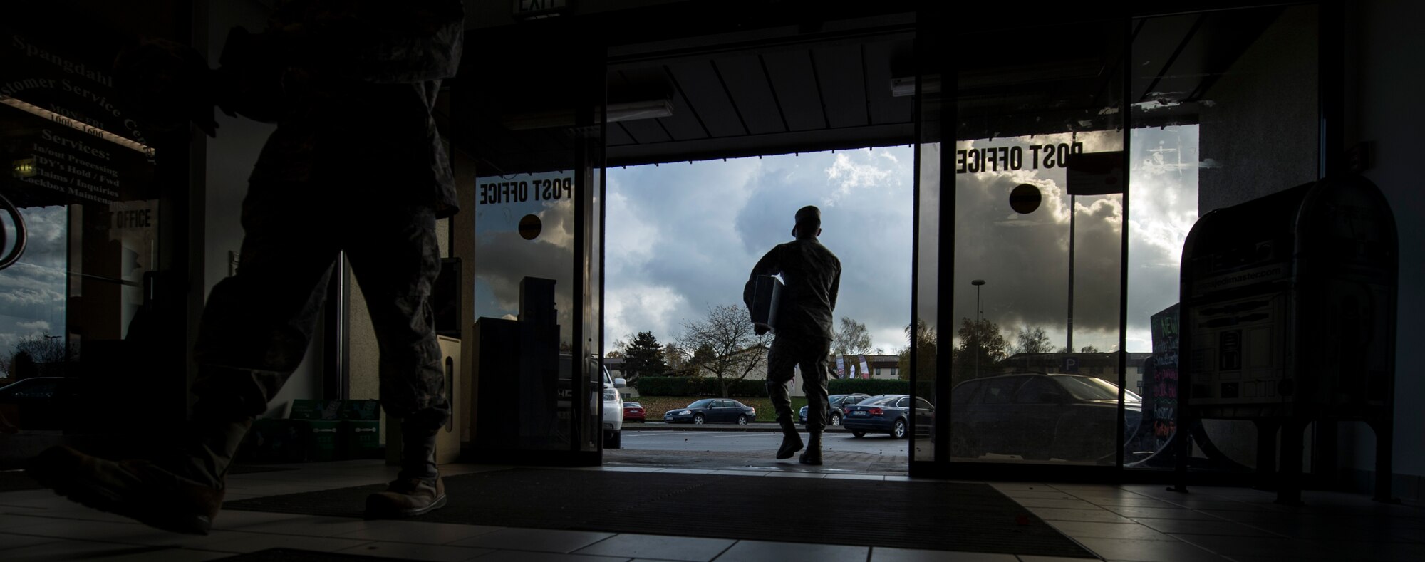 Customers walk into the post office at Spangdahlem Air Base, Germany, Nov. 9, 2015. One of the ways the post office helps their customers is by extending the finance window hours during the holidays. (U.S. Air Force photo by Senior Airman Rusty Frank/Released)