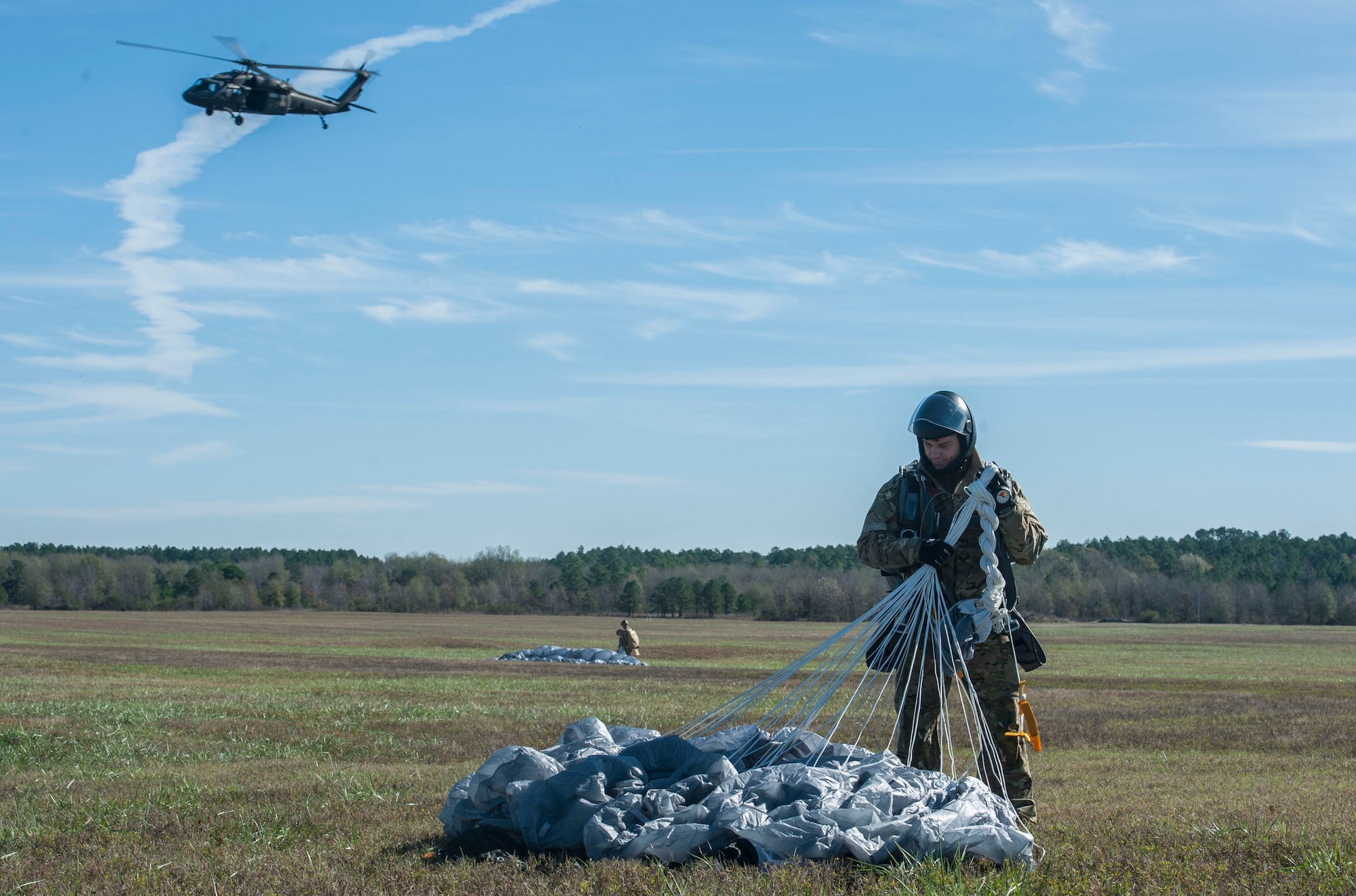 U.S. Air Force Tech. Sgt. Nick Gianoli, 375th Operations Support Squadron survival, evasion, resistance and escape non-commissioned officer in charge, gathers his parachute after conducting a military free-fall jump from a UH-60 Blackhawk Nov. 12, 2015, at Camp Robinson, Ark. SERE specialists accomplish up to 12 jumps each year in order to maintain MFF qualifications. (U.S. Air Force photo by Airman 1st Class Mercedes Muro) 