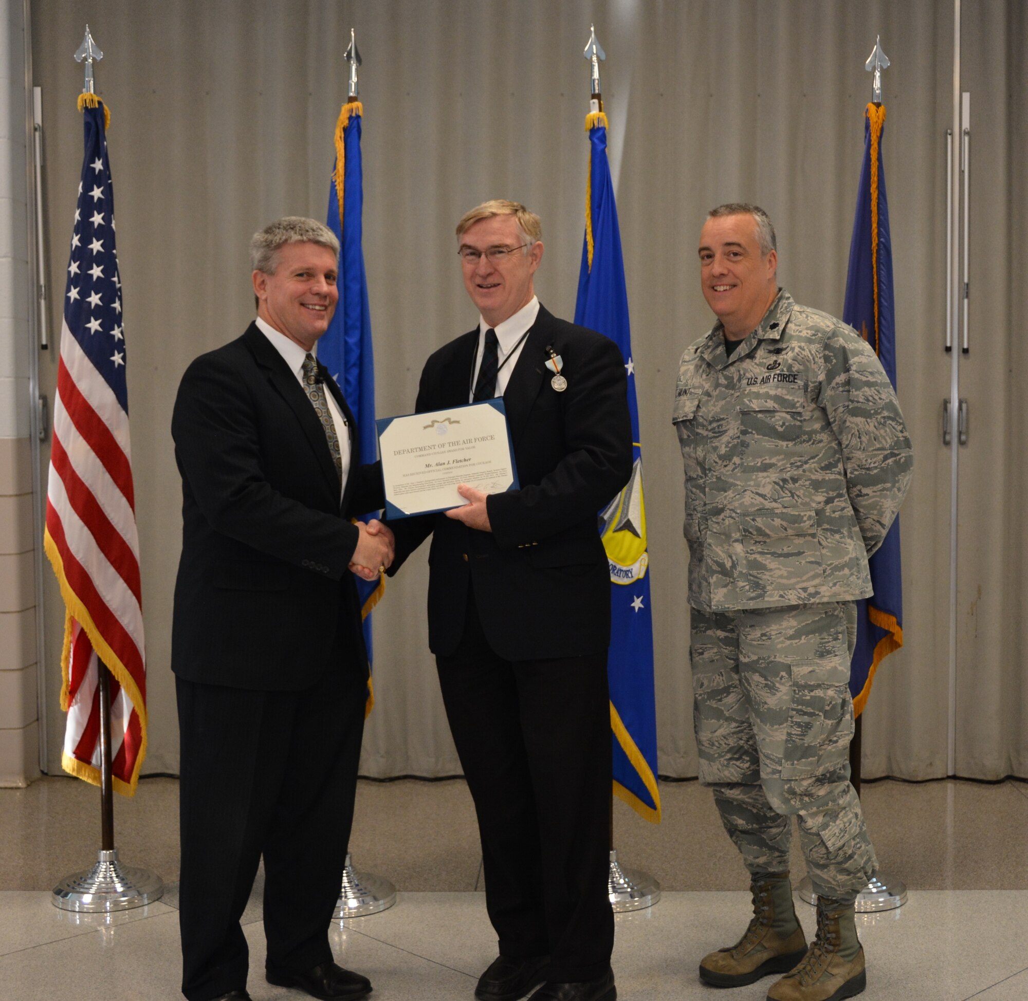 Mr. Thomas Lockhart, Director of the AFRL Materials and Manufacturing Directorate (left) and Lt. Col. Frederick Hunt present Mr. Alan Fletcher with the Command Civilian Award for Valor for his quick-thinking response to save a fellow driver from possible harm.  Mr. Fletcher incurred numerous injuries as a result of his actions.  (U.S. Air Force photo/Lori
Hughes)
