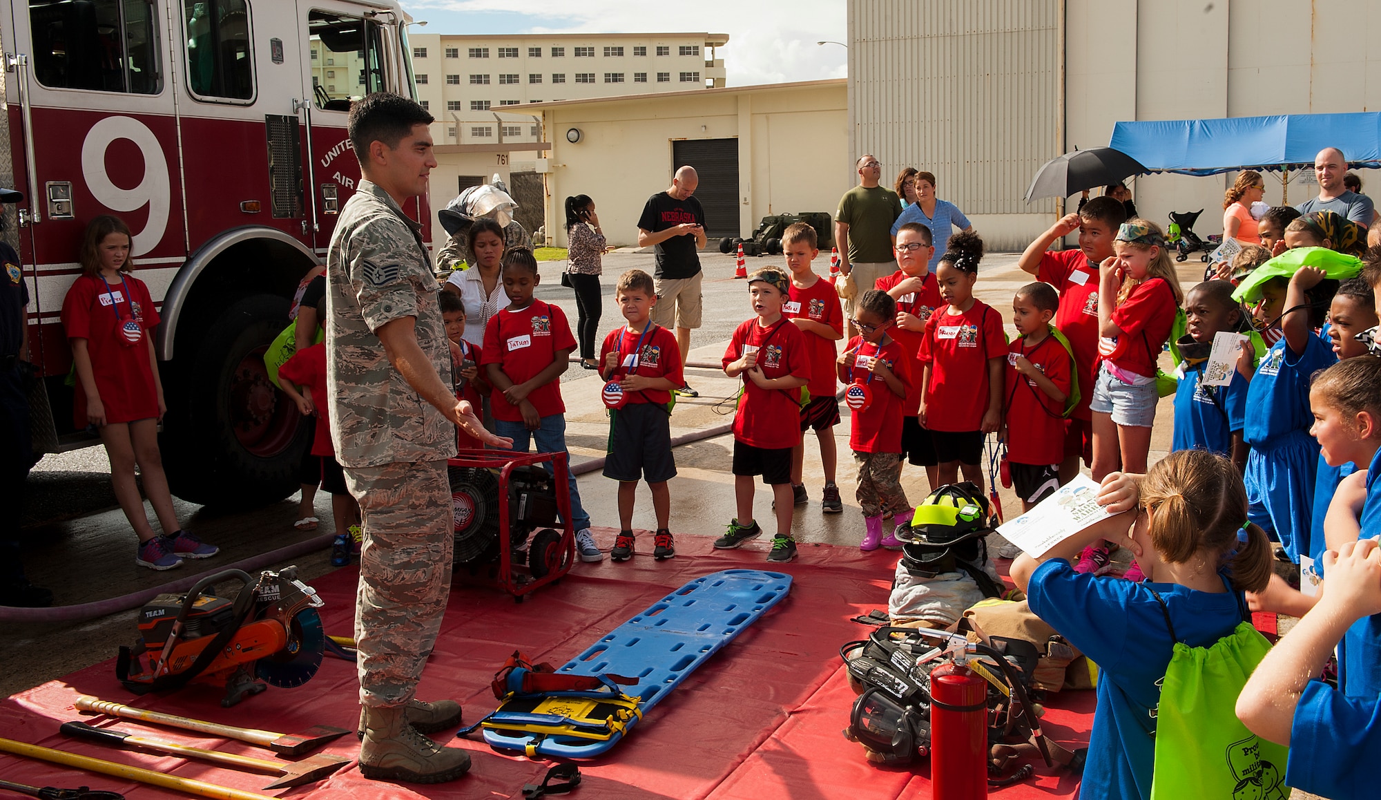 U.S. Air Force Staff Sgt. Juan Duarte, 18th Civil Engineer Squadron firefighter, teaches children about the different equipment that firefighters use on the job at Skoshi Warrior Nov. 14, 2015, at Kadena Air Base, Japan. This event helps military children understand what their parents go through while deploying and day-to-day operations by giving them a hands-on experience at some of the tasks military members go through. (U.S. Air Force photo by Airman 1st Class Corey M. Pettis)