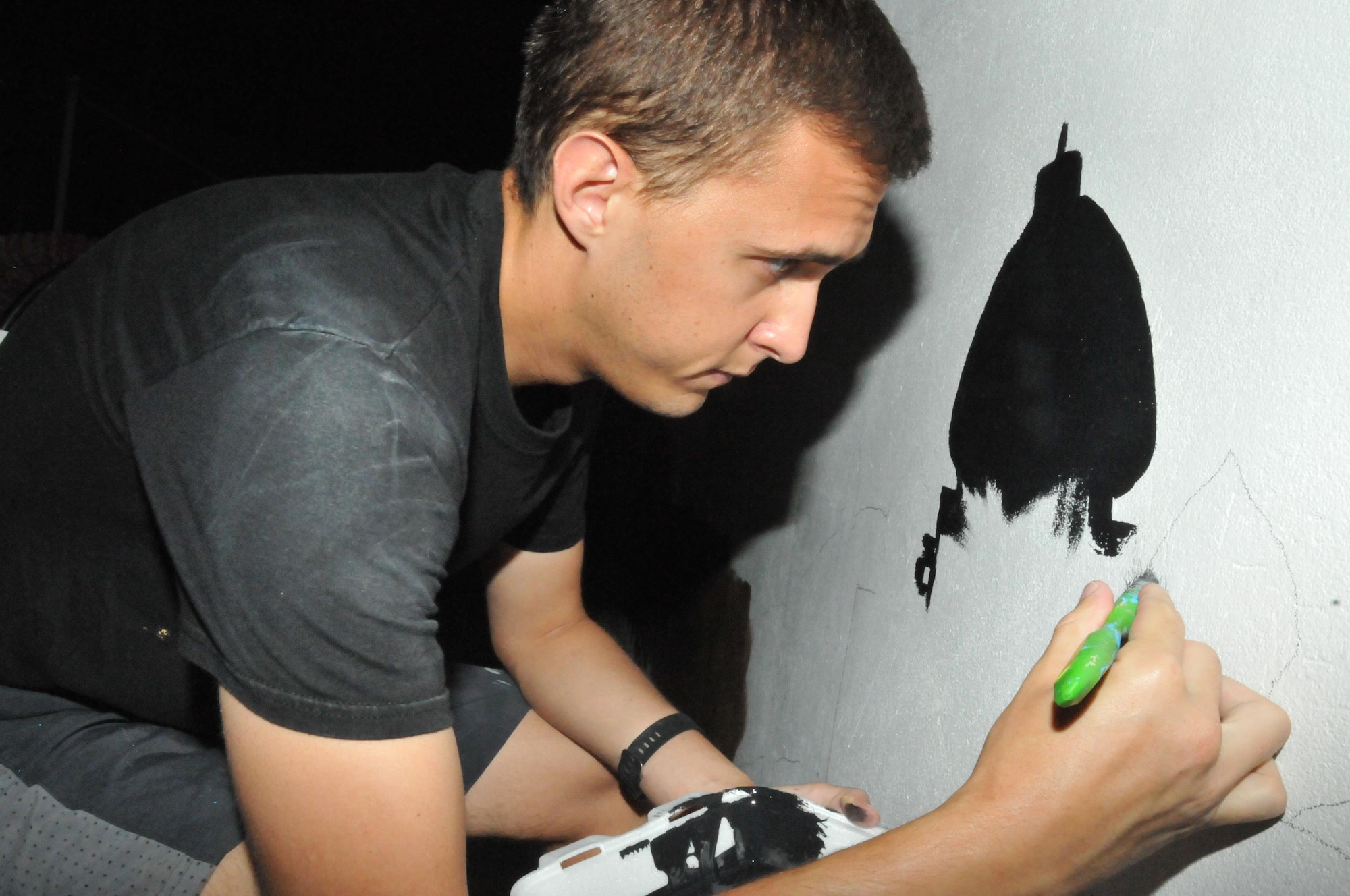 Capt. Tyler George, 340th Expeditionary Air Refueling Squadron, helped with painting the interior walls of the coalition compound pool Nov. 18 at Al Udeid Air Base, Qatar. George said helping paint the mural was a good way to volunteer and meet people. Airmen from various units came out to paint the mural. (U.S. Air Force photo by Tech. Sgt. Terrica Y. Jones/Released)