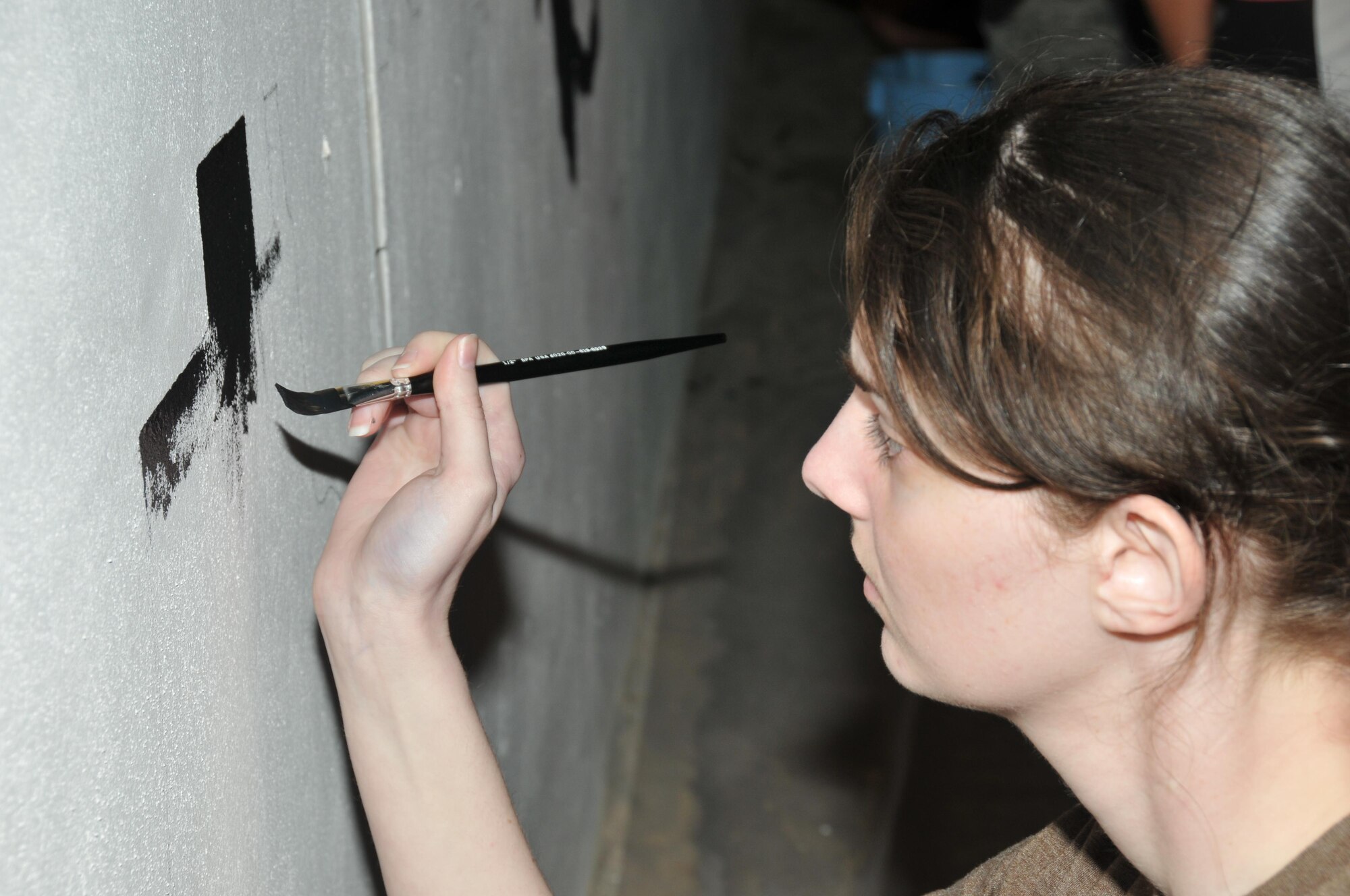 Airman 1st Class Mary Daugherty, 379th Expeditionary Communications Squadron, paints one of the sections of the desert oasis Nov. 14 at Al Udeid Air Base, Qatar. Daugherty joined six airmen at the pool mural. The mural is expected to be completed by the end of November.  (U.S. Air Force photo by Tech. Sgt. Terrica Y. Jones/Released)