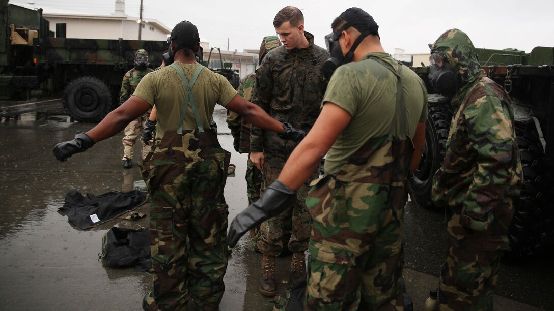 Lance Cpl. William Hony, center, chemical, biological, radiological and nuclear chief with Marine Wing Support Squadron 171, inspects reconnaissance, surveillance and decontamination Marines mission-oriented protective postures four gear during a simulated chemical attack at the MWSS-171 motor transportation wash rack at Marine Corps Air Station Iwakuni, Japan, Nov. 18, 2015. As part of an operational decontamination exercise, the RSD team decontaminated vehicles, and performed a MOPP exchange to thoroughly review each other’s PPE and ensure Marines could safely resume normal operations.