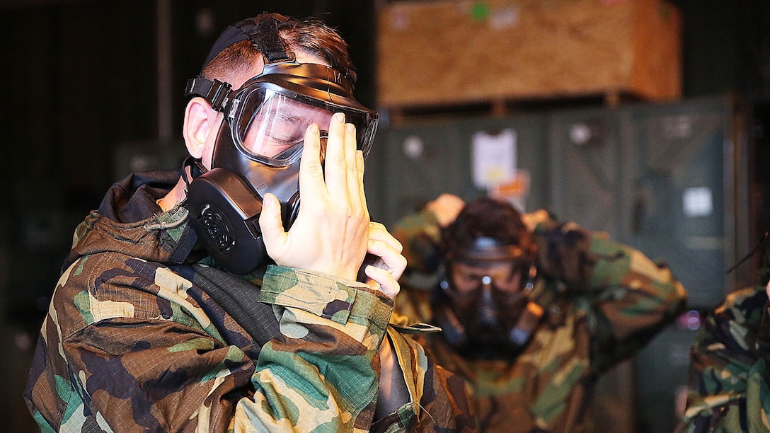A reconnaissance, surveillance and decontamination Marine dons mission-oriented protective postures four gear during a simulated chemical attack at the Marine Wing Support Squadron 171 motor transportation at Marine Corps Air Station Iwakuni, Japan, Nov. 18, 2015. As part of Marine Corps Order 3400.3G, units are required to integrate potential CBRN situations into exercises and train to accomplish their assigned mission essential tasks in a CBRN environment.