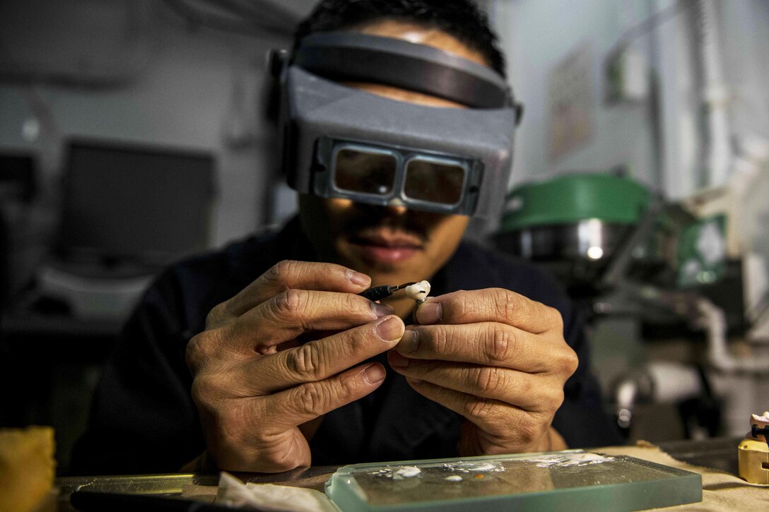 U.S. Navy Chief Noel Toledo uses a brush to stack porcelain on a molar in the dental lab aboard the USS Ronald Reagan in the waters south of Japan, Nov. 18, 2015. The carrier and its embarked air wing, Carrier Air Wing 5, provide a combat-ready force to protect and defend the collective maritime interests of the U.S. and its allies and partners in the Indo-Asia-Pacific region. Toledo is the ship's dental department's leading chief petty officer. U.S. Navy photo by Petty Officer 3rd Class Ryan McFarlane
