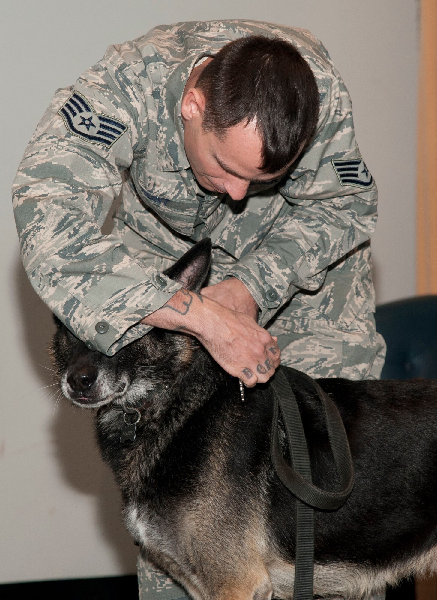 Staff Sgt. Scott Hunt, a 71st Security Forces Squadron military working dog handler, pins an Air Force Achievement Medal onto military working dog Maxik during the pup’s retirement ceremony Nov. 10 in the Base Auditorium. Maxik served seven years of distinguished service in the U.S. Air Force with two deployments. 