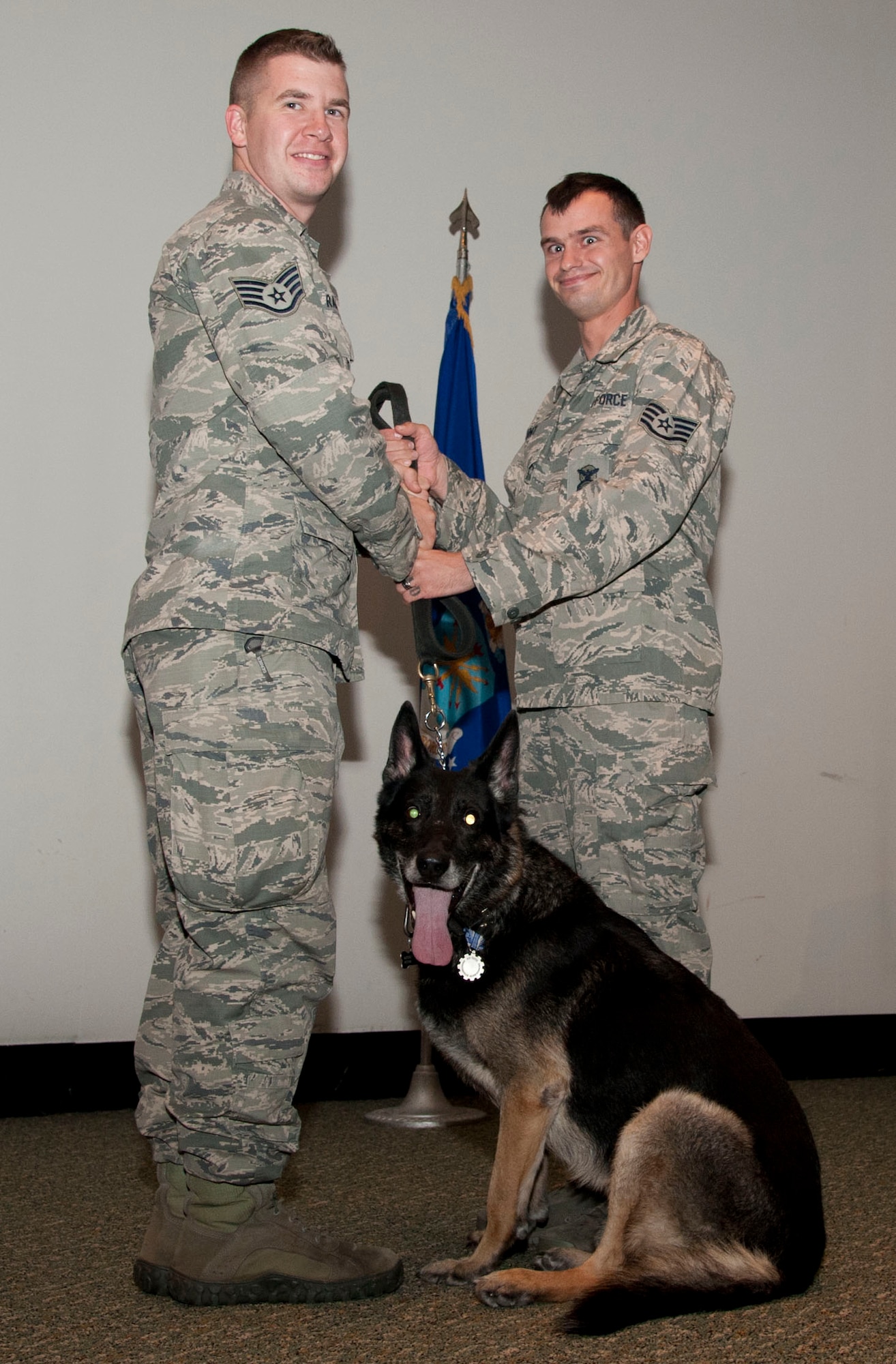 Staff Sgt. Scott Hunt (right), a 71st Security Forces Squadron military working dog handler, passes the leash of military working dog Maxik to Staff Sgt. Marshall Rains, Maxik’s previous handler, during the dog’s retirement ceremony Nov. 10 in the Base Auditorium. Rains served two years with Maxik and adopted him after the retirement.