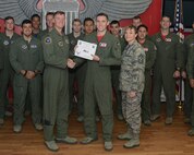 First Lt. Bradford Smith, center, 434th Flying Training Squadron check flight scheduler, poses with Col. Thomas Shank, left, 47th Flying Training Wing commander, and Chief Master Sgt. Teresa Clapper, 47th FTW command chief, after accepting the “XLer of the Week” award, here, Nov. 4, 2015. The “XLer” is a weekly award chosen by wing leadership and is presented to those who consistently make outstanding contributions to their unit and Laughlin. (U.S. Air Force photo by Airman 1st Class Brandon May)