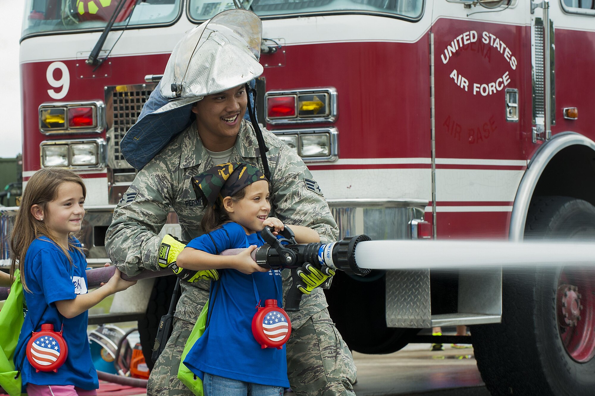 U.S. Air Force Senior Airman James Permito, 18th Civil Engineer Squadron firefighter, holds the water hose steady as children shoot at cones during Skoshi Warrior Nov. 14, 2015, at Kadena Air Base, Japan. Skoshi Warrior is an annual event for military children and provides a fun environment for children to experience the deployment process their parents go through when tasked to deploy. (U.S. Air Force photo by Airman 1st Class Corey M. Pettis/Released)