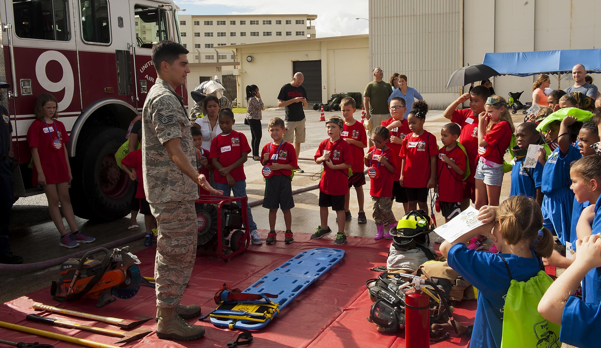 U.S. Air Force Staff Sgt. Juan Duarte, 18th Civil Engineer Squadron firefighter, teaches children about the different equipment that firefighters use on the job at Skoshi Warrior Nov. 14, 2015, at Kadena Air Base, Japan. This event helps military children understand what their parents go through while deploying and day-to-day operations by giving them a hands-on experience at some of the tasks military members go through. (U.S. Air Force photo by Airman 1st Class Corey M. Pettis/Released)