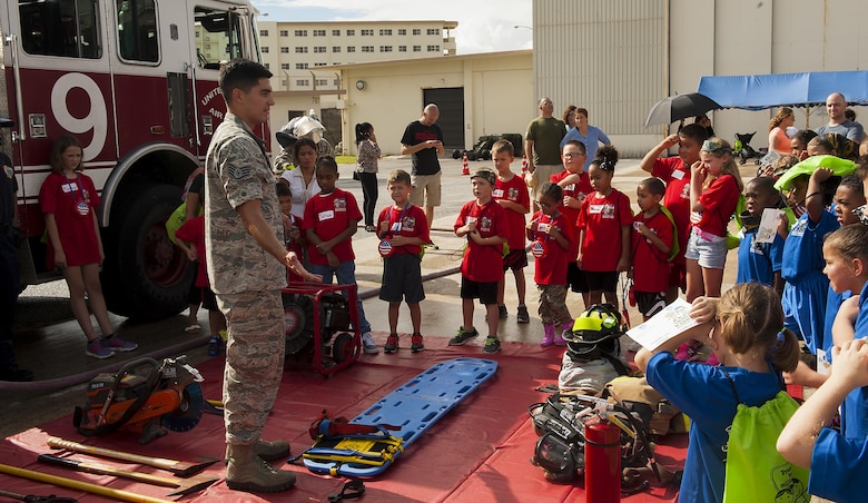 U.S. Air Force Staff Sgt. Juan Duarte, 18th Civil Engineer Squadron firefighter, teaches children about the different equipment that firefighters use on the job at Skoshi Warrior Nov. 14, 2015, at Kadena Air Base, Japan. This event helps military children understand what their parents go through while deploying and day-to-day operations by giving them a hands-on experience at some of the tasks military members go through. (U.S. Air Force photo by Airman 1st Class Corey M. Pettis/Released)